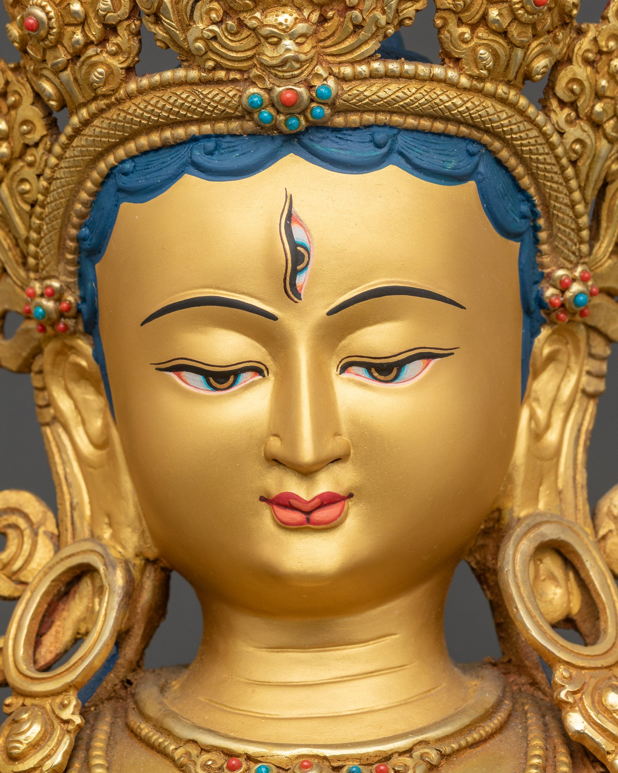 White Tara statue face close-up, serene gold-painted expression, Himalayan art