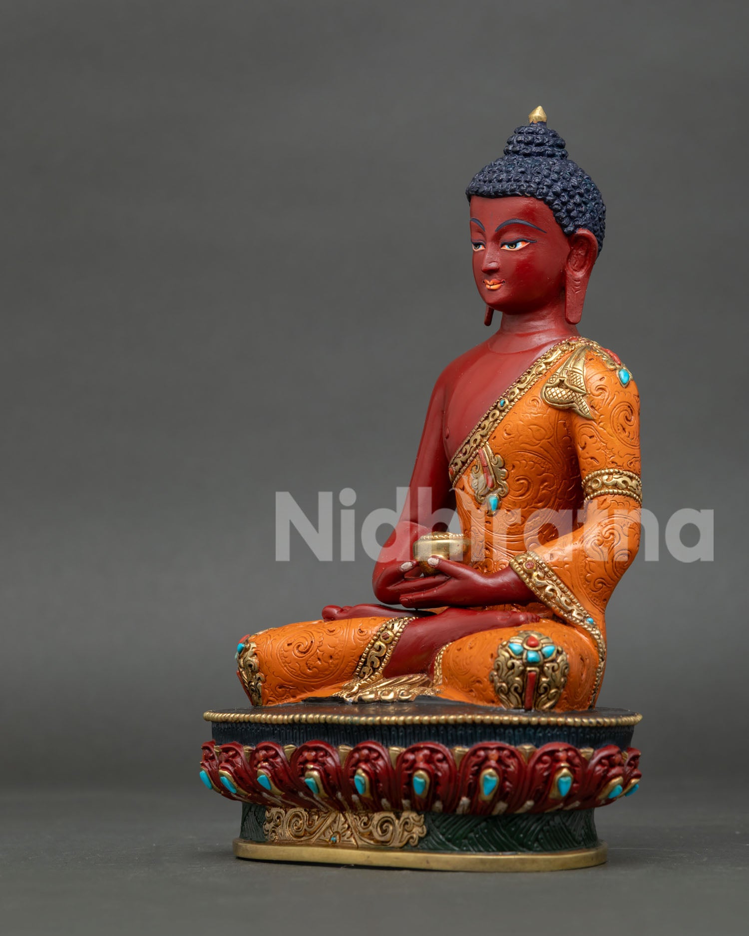 Amitabha Buddha statue with red painted body and intricate orange robe artwork