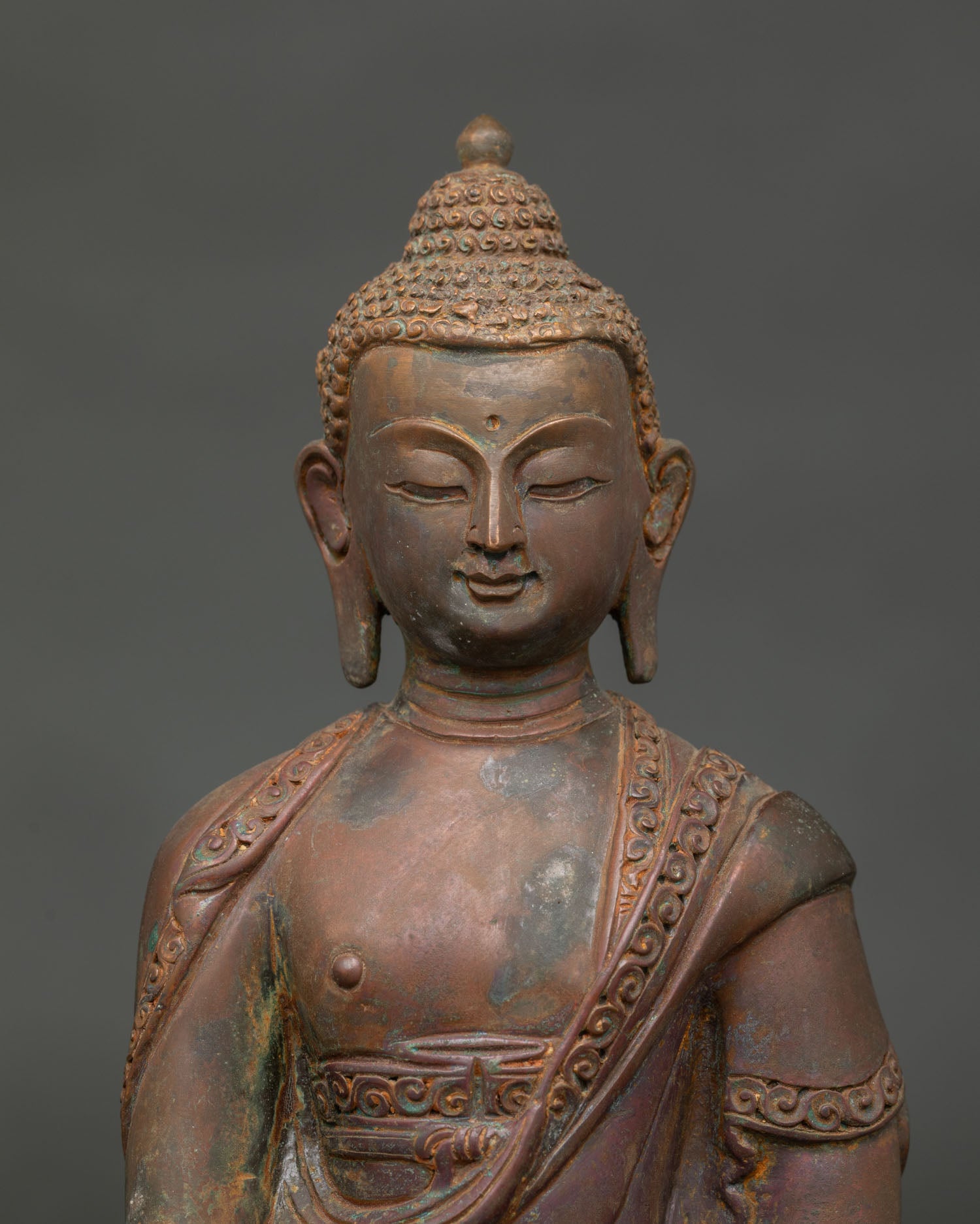 Amitabha Buddha statue close up showing hand carved monk robe and serene face.