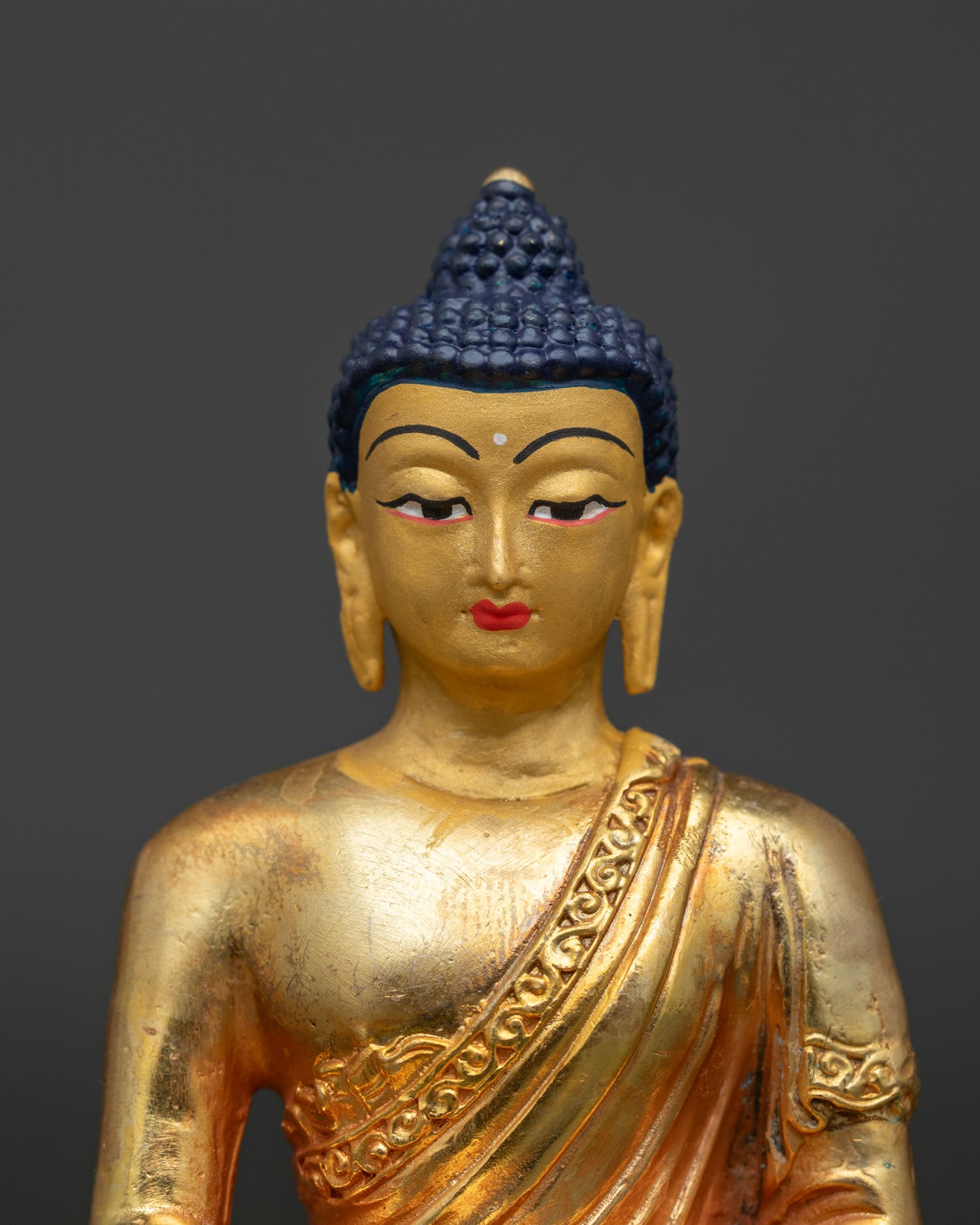 Amitabha Buddha statue close up with gold painted face and intricate Newari craftsmanship.