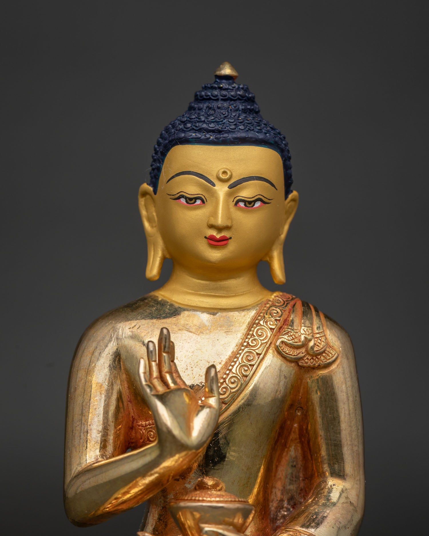 Amoghasiddhi Buddha statue close up 24K gold painted face and serene expression.