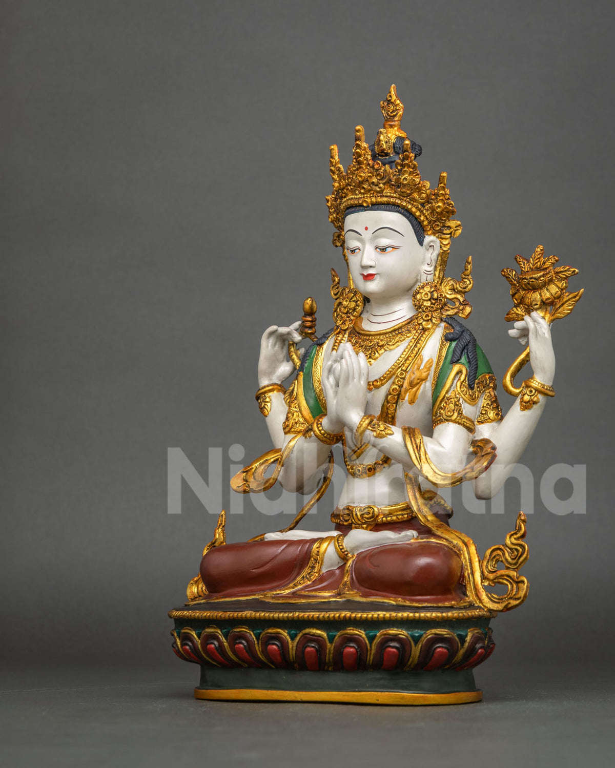 Angled side view of four-armed Chenrezig statue in anjali mudra on lotus base