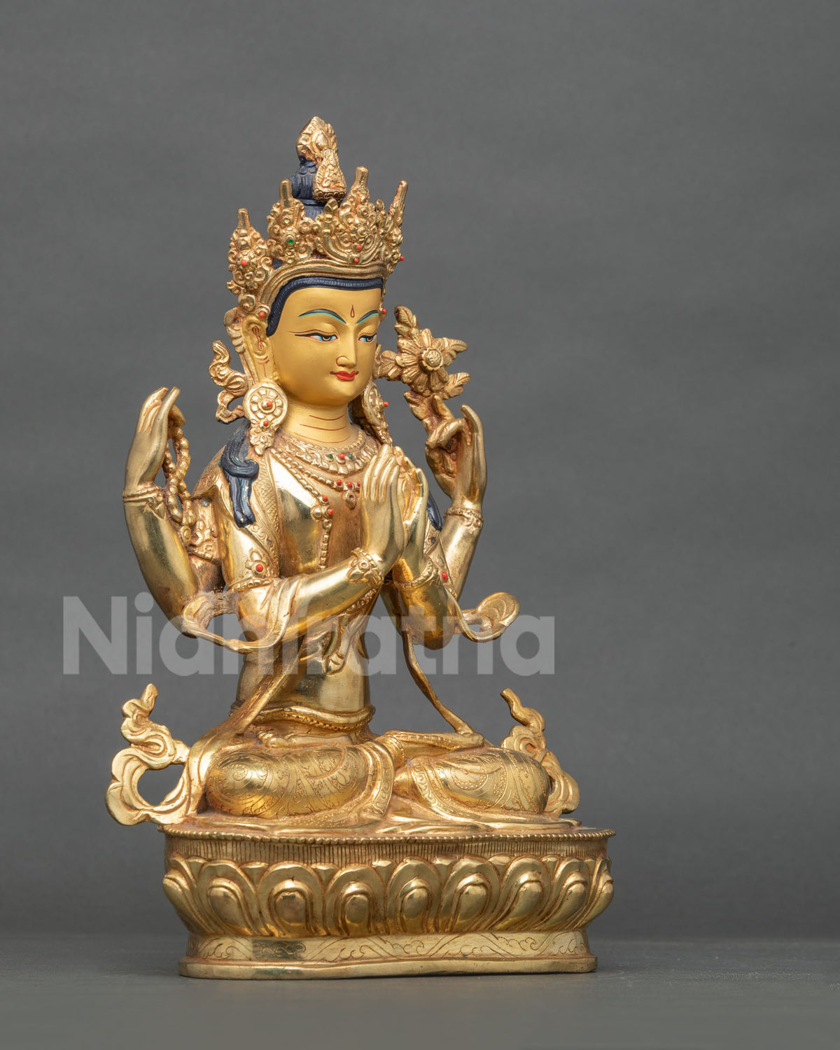 Angled side view of gilded Chenrezig Buddha statue seated on lotus pedestal holding a flower