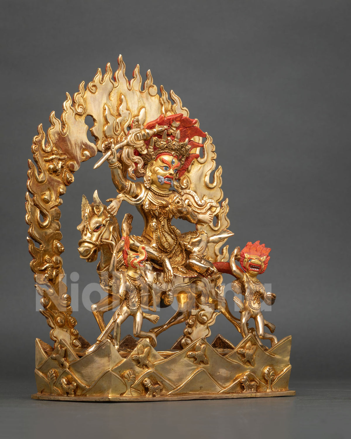 Angled side view of gold Palden Lhamo statue with flaming halo and mountain base