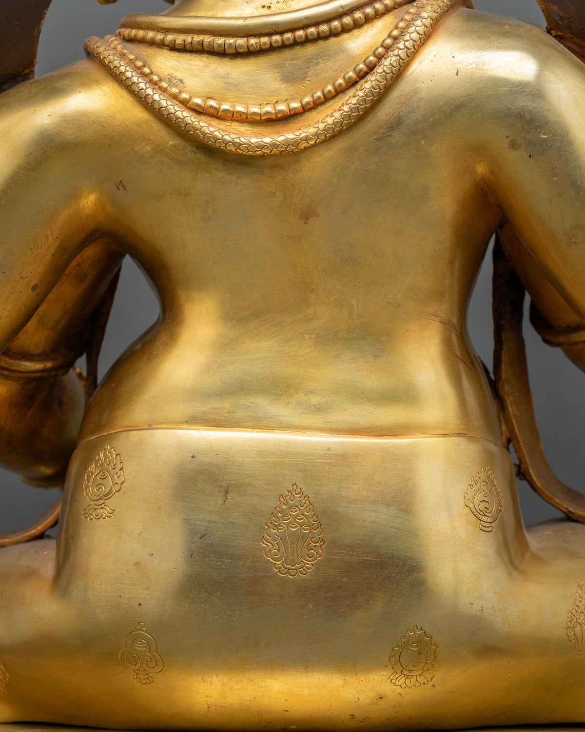 Back of Ganesh statue with engraved auspicious symbols and smooth 24K gold fire-gilded finish