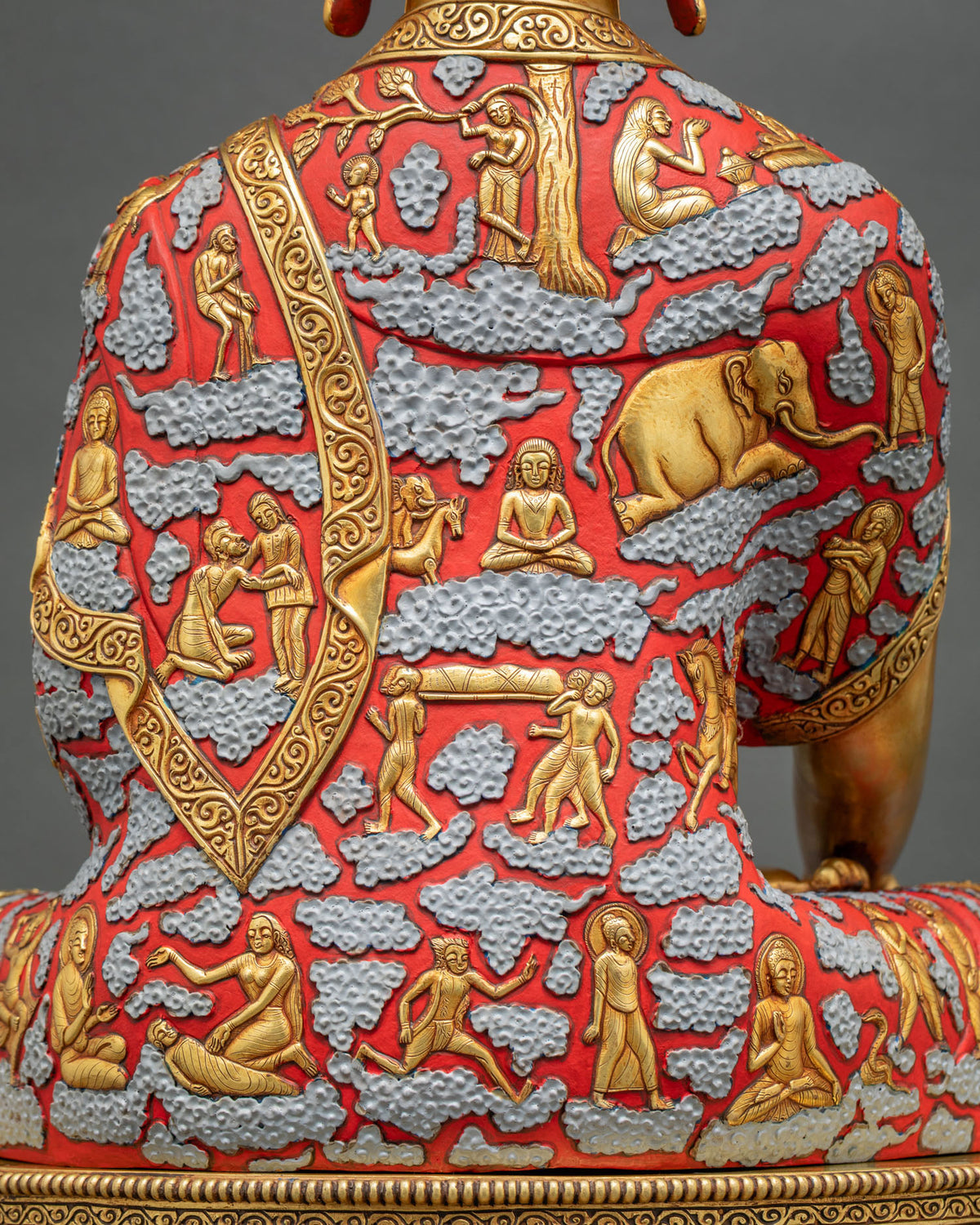 Back of Shakyamuni Buddha statue robe with gold elephant, tree, and sculpted life story scenes