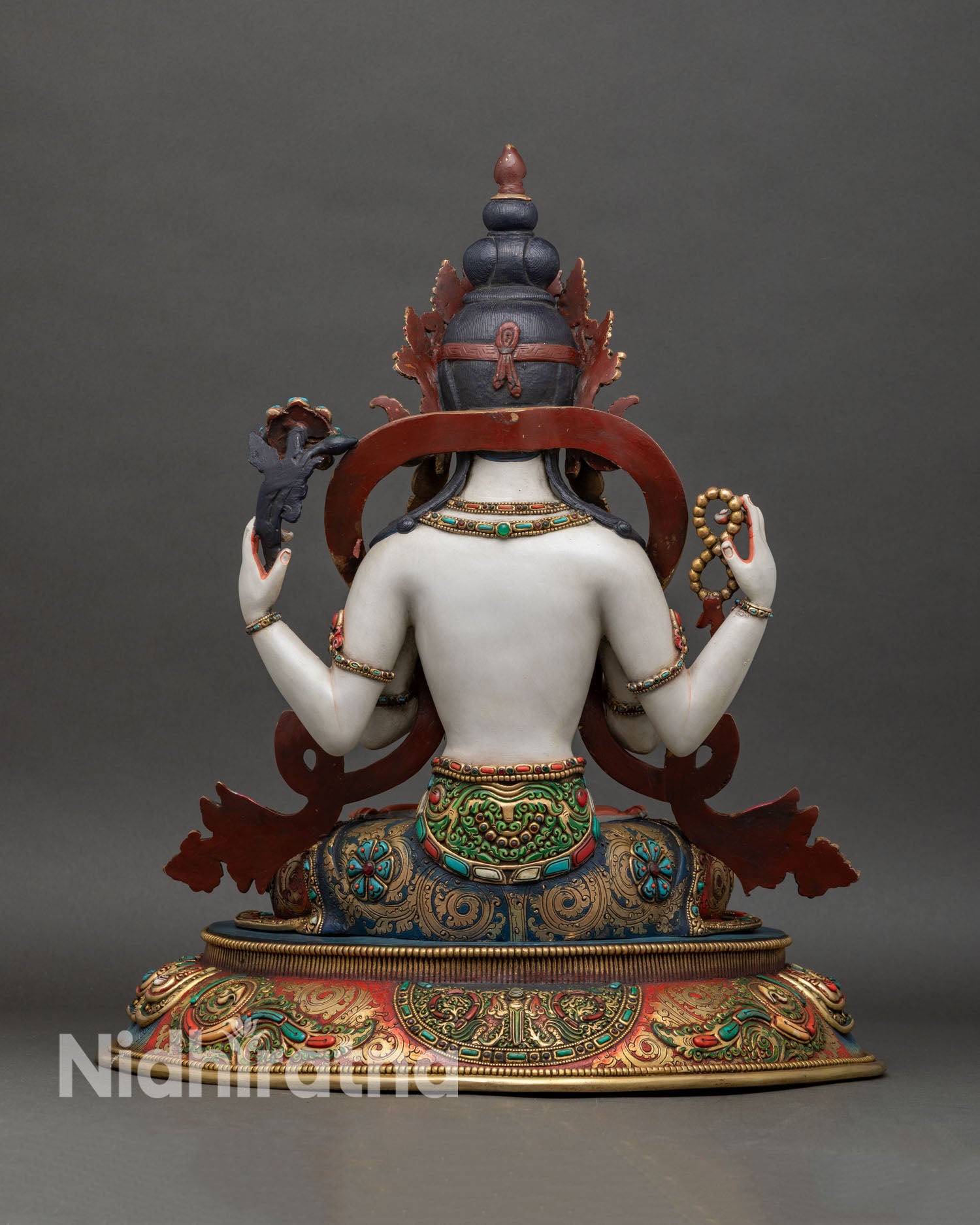 Back view of Chenrezig statue showing ornate halo, robe details, and sculpted lotus base
