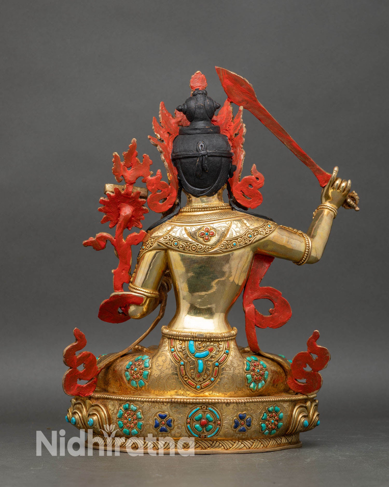 Back view of Manjushri statue with intricate robes and five jewel crown in Nepalese art
