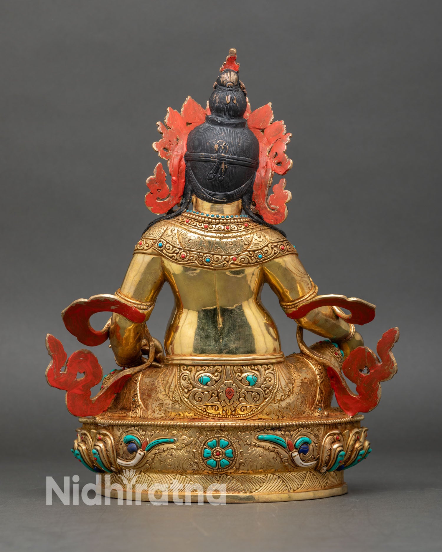 Back view of Dzambhala statue with detailed robe folds and throne carving