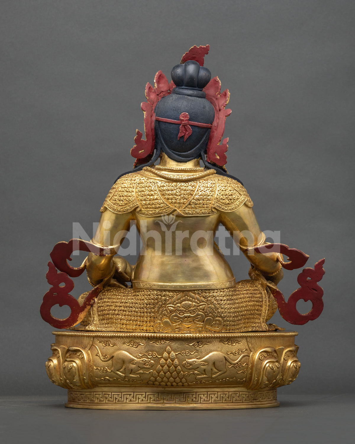 Back view of gold fire-gilded Dzambhala copper statue with engraved robes and lotus base