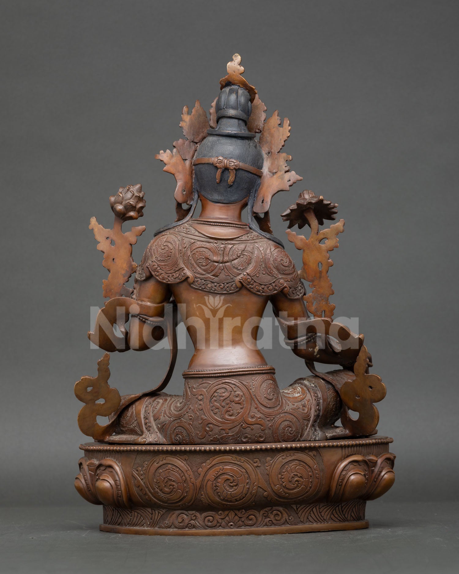 Back view of Green Tara statue displaying intricate robe patterns and copper craftsmanship