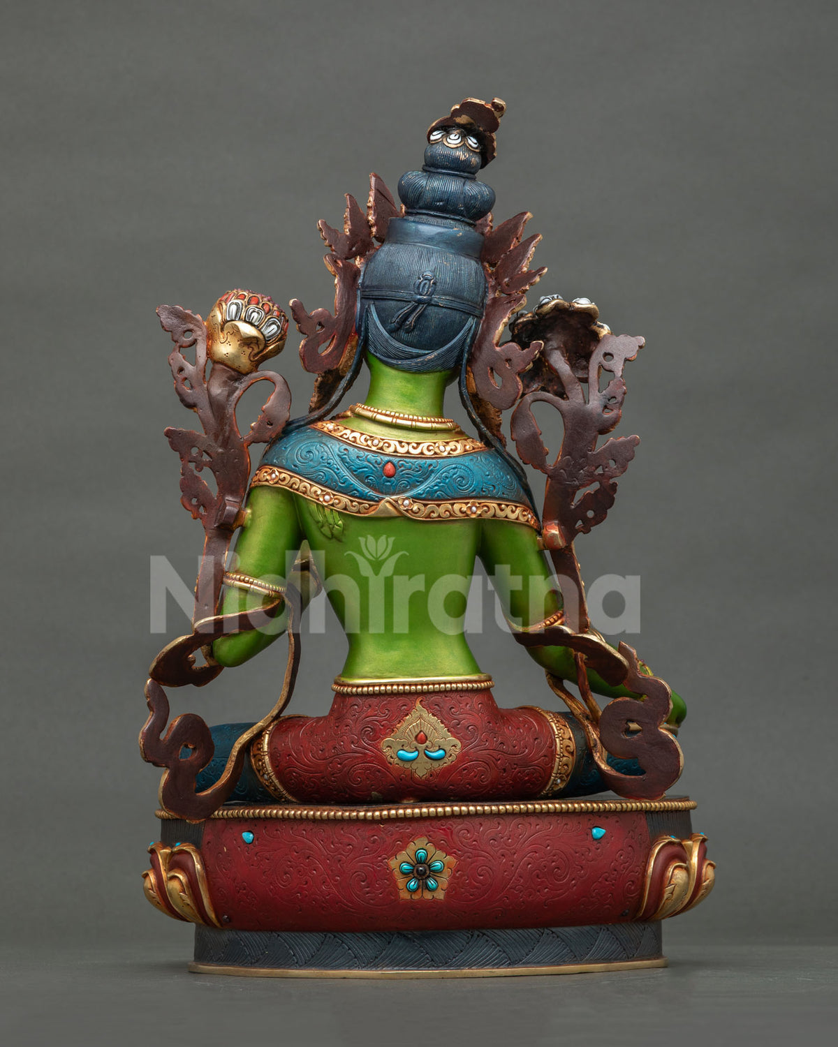 Back view of Green Tara statue with ornate backrest, red and blue robes and lotus base