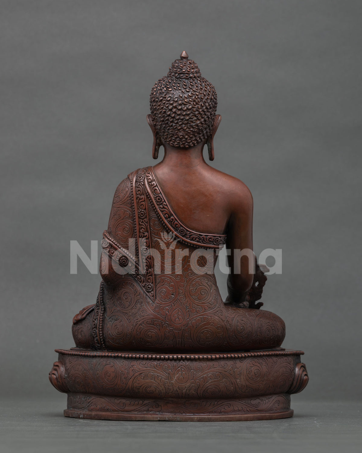 Back view of hand-cast copper Medicine Buddha statue showing detailed robe and lotus base