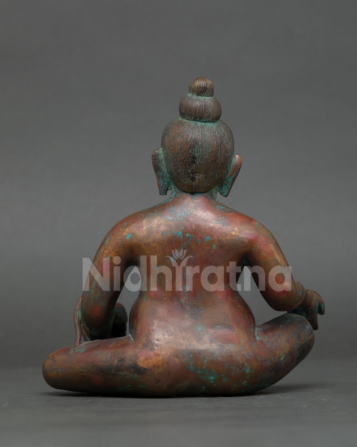 back view of handmade dzambhala statue showing engraved copper artwork and lotus base