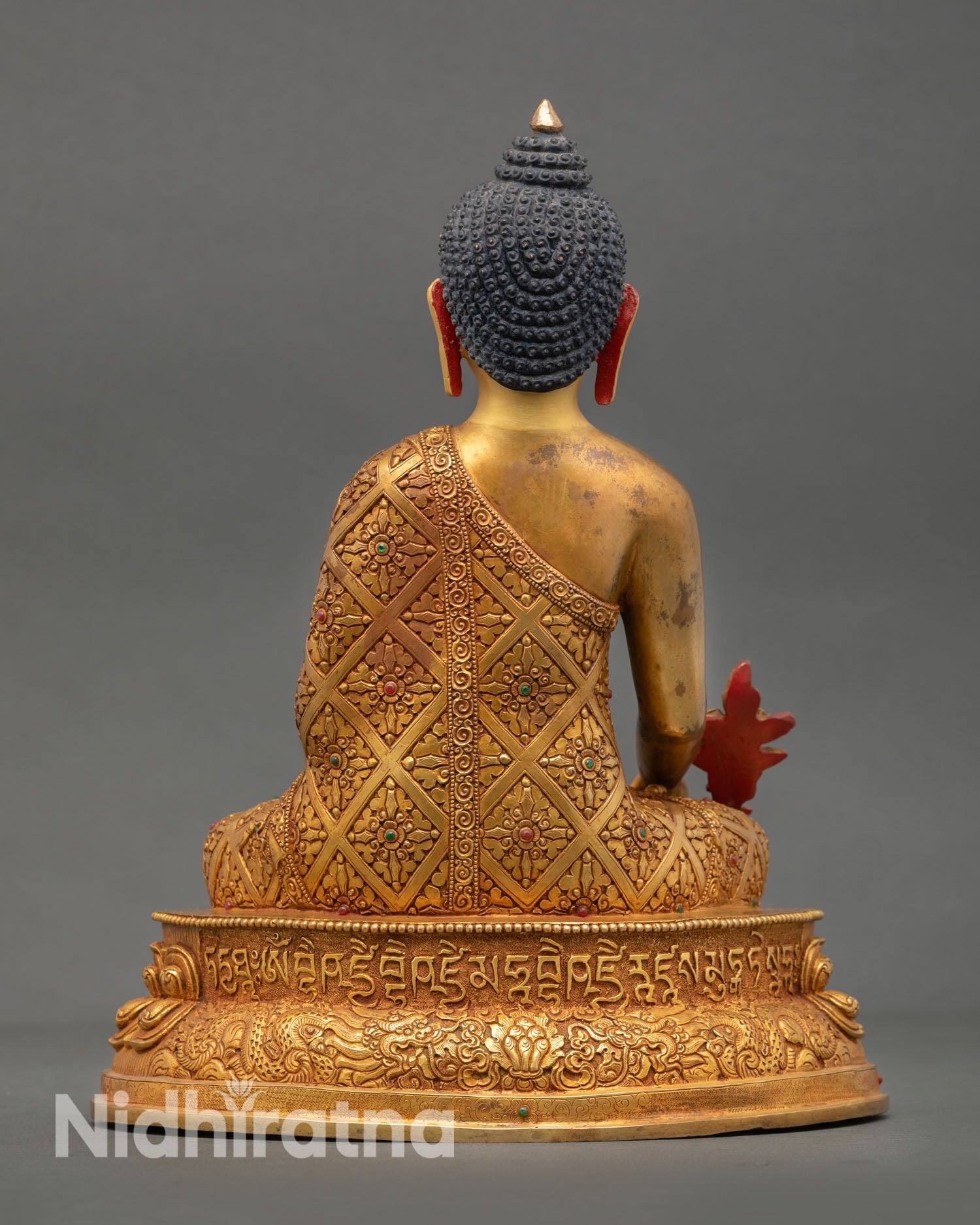Back view of handmade Medicine Buddha statue featuring ornate copper detailing richly carved lotus pedestal