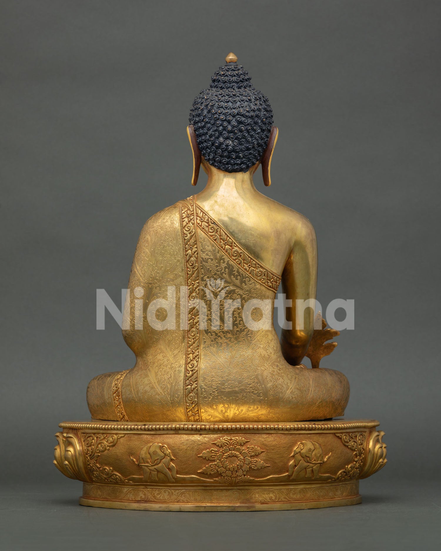 back view of medicine buddha statue with detailed robe carvings and lotus pedestal
