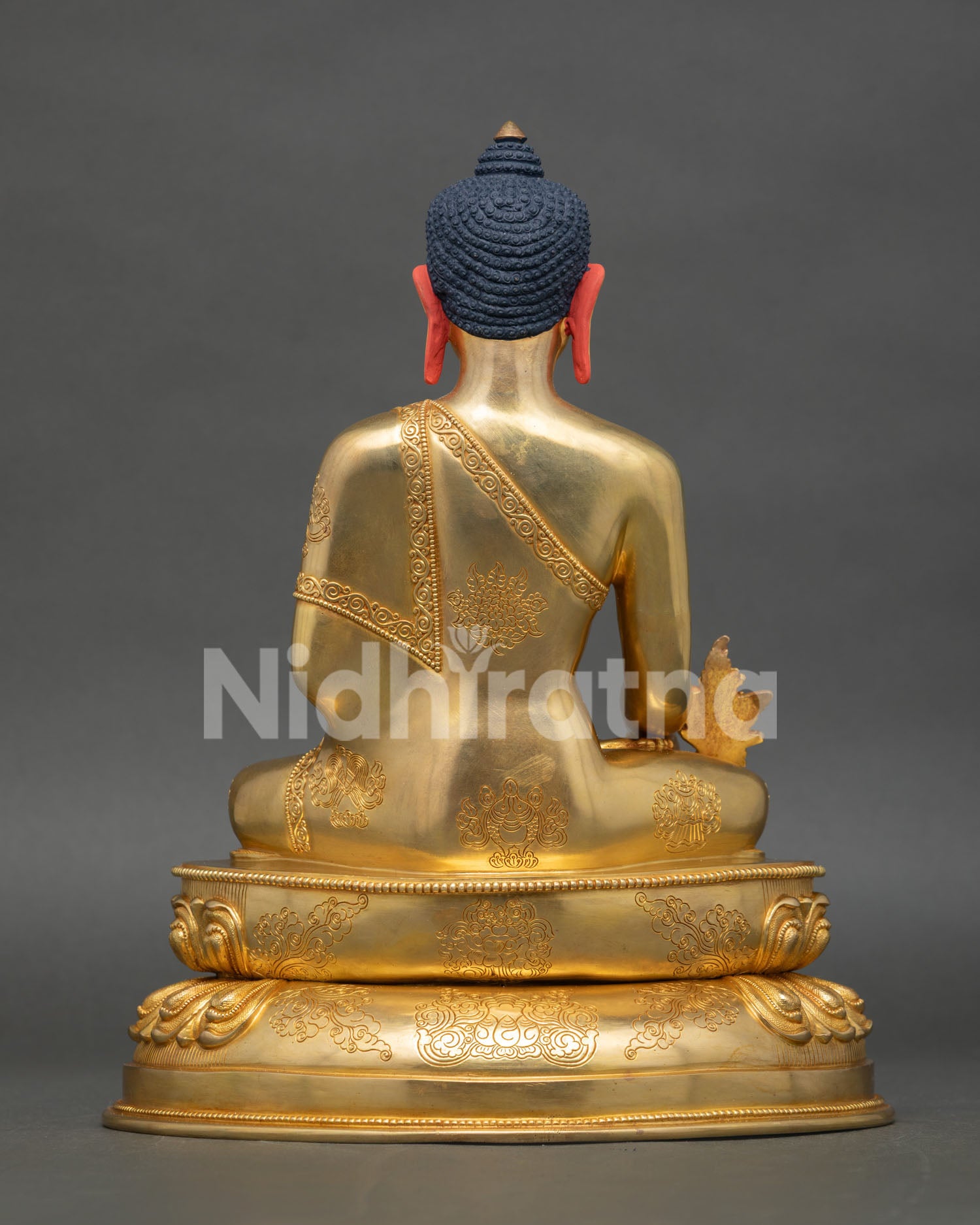 back view of medicine buddha statue with engraved lotus throne and traditional himalayan design