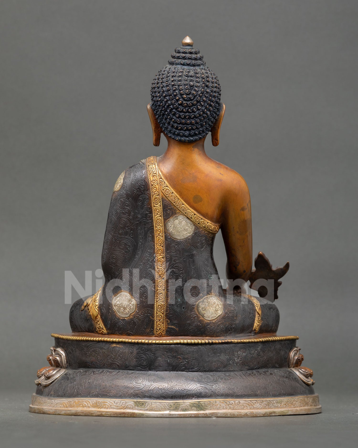 back view of oxidized copper medicine buddha statue with detailed robe patterns