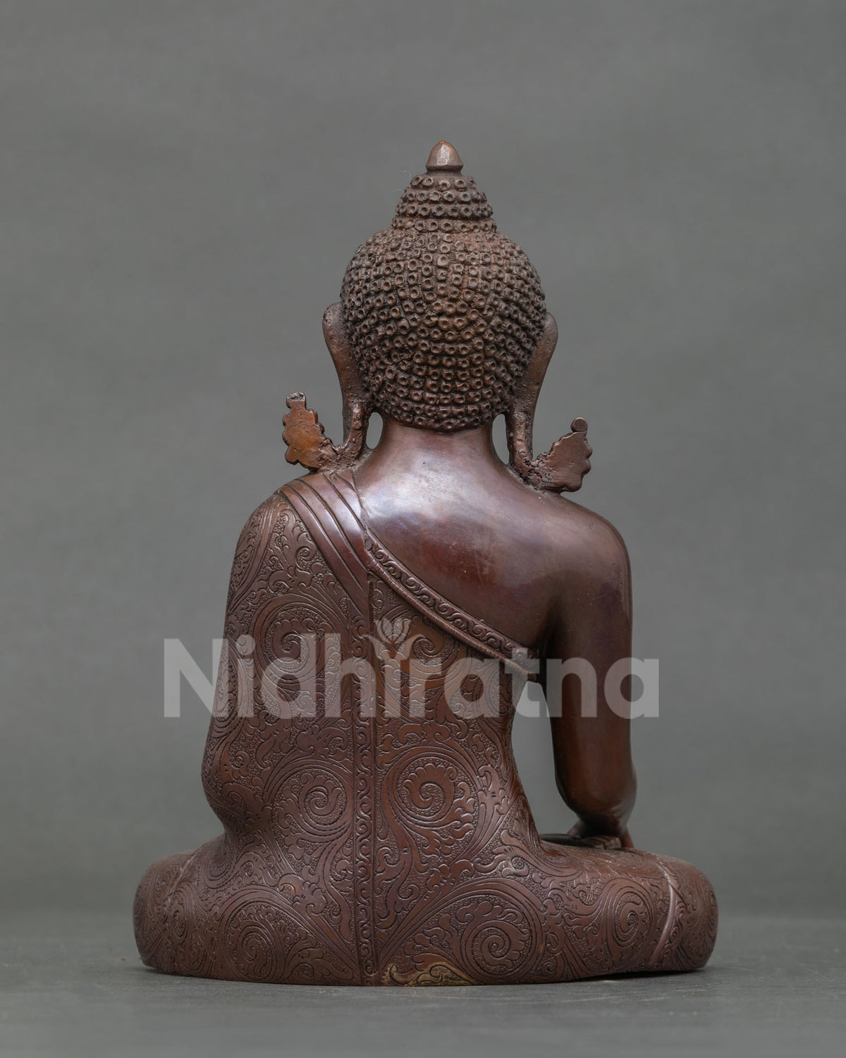 Back view of oxidized copper Shakyamuni Buddha statue showing carved robe and ushnisha