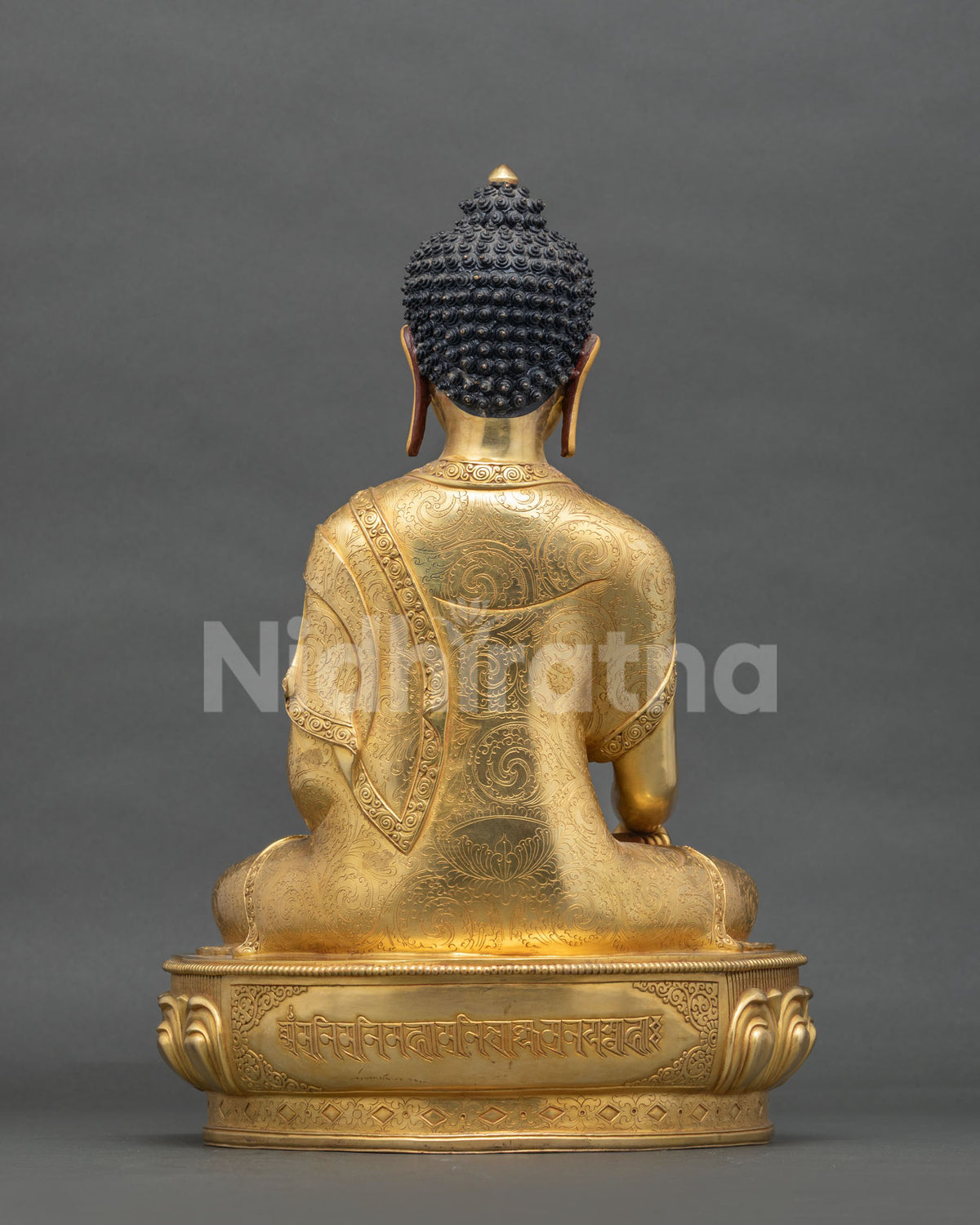 Back view of Shakyamuni Buddha statue with engraved mantra on lotus base and hand-chased robe