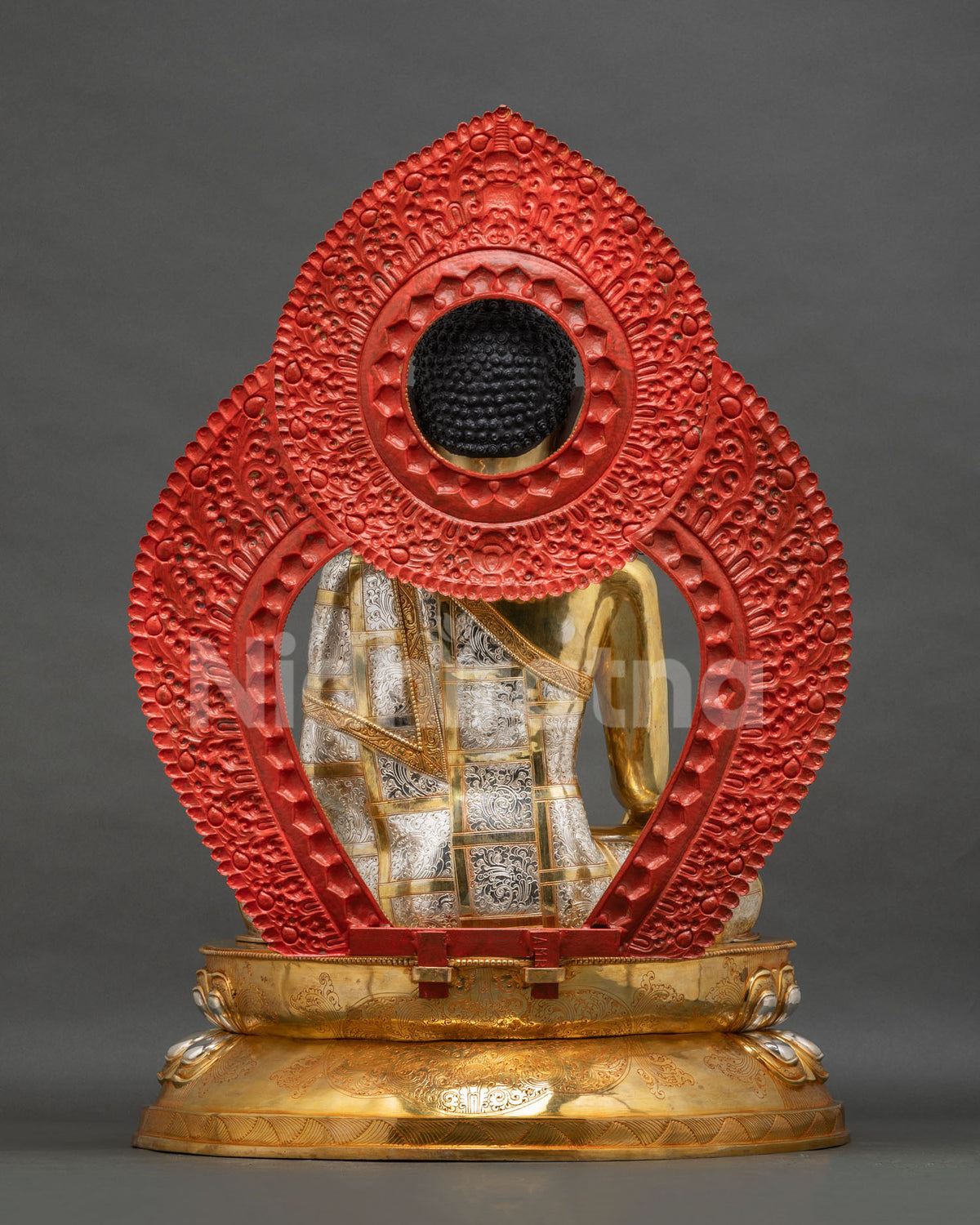 Back view of Shakyamuni Buddha statue with engraved silver robe and red-painted halo