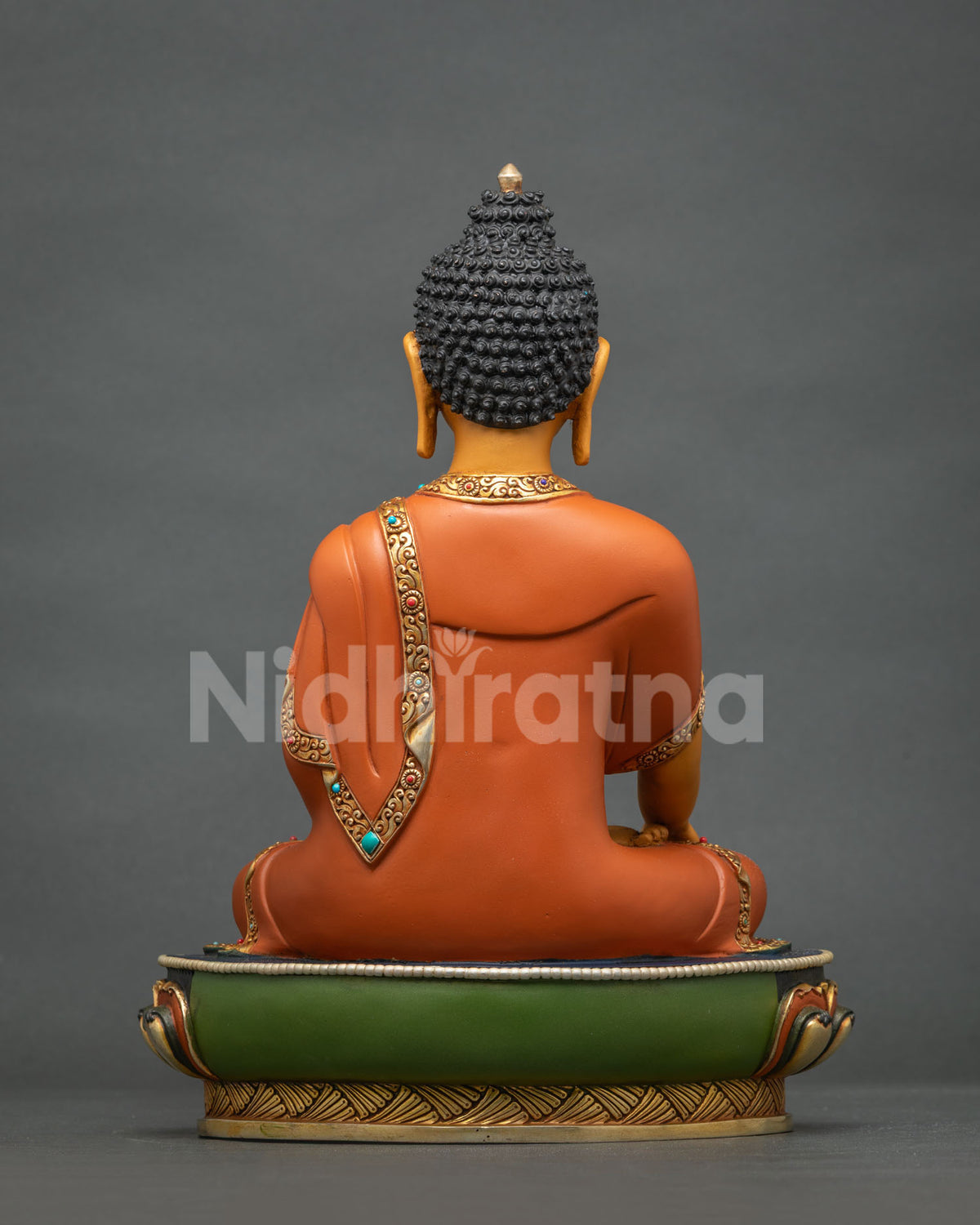 Back view of Shakyamuni Buddha statue with gilded robe trim and green lotus base