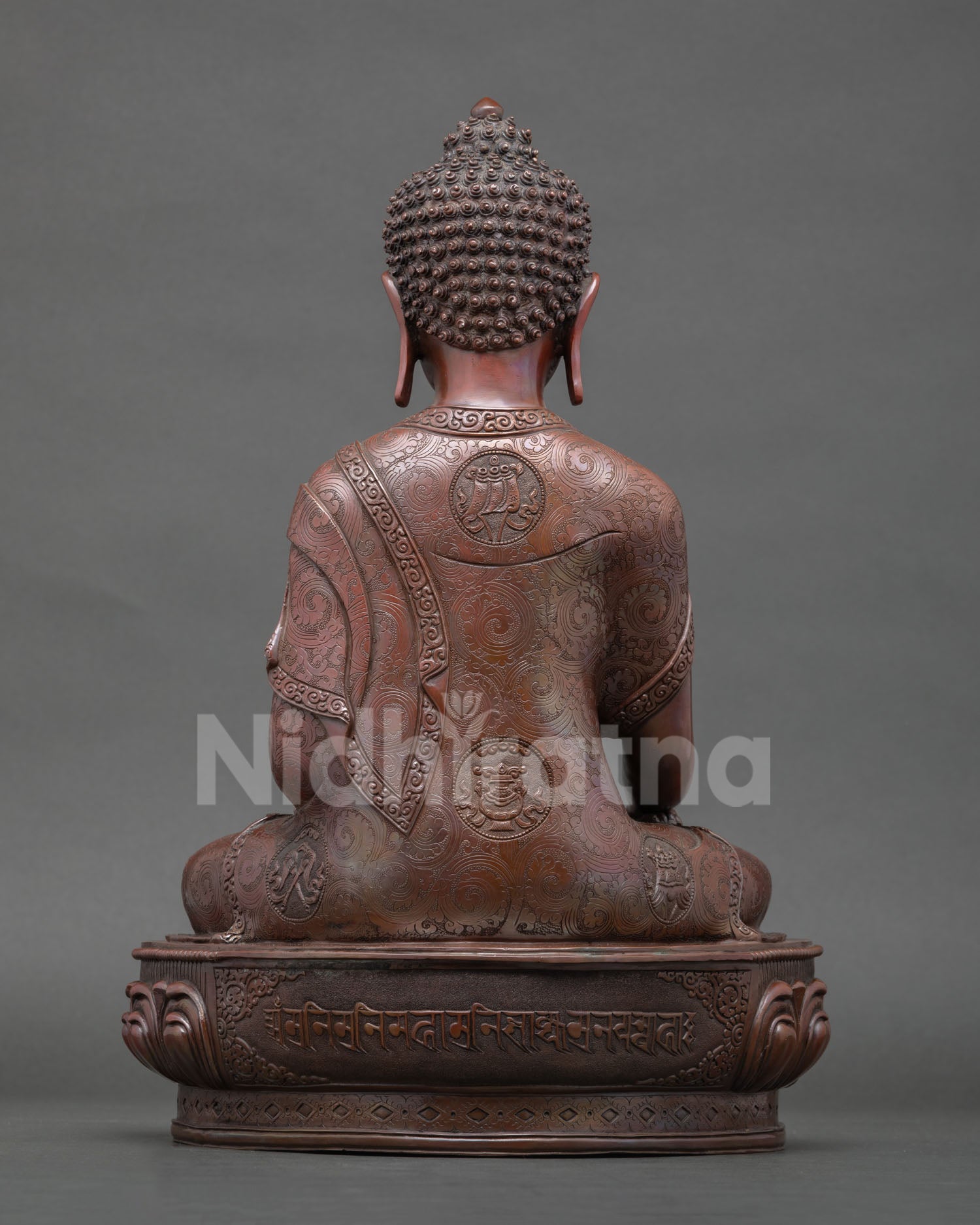 Back view oxidized copper Buddha statue showing engraved lotus base and sacred Tibetan mantra carving