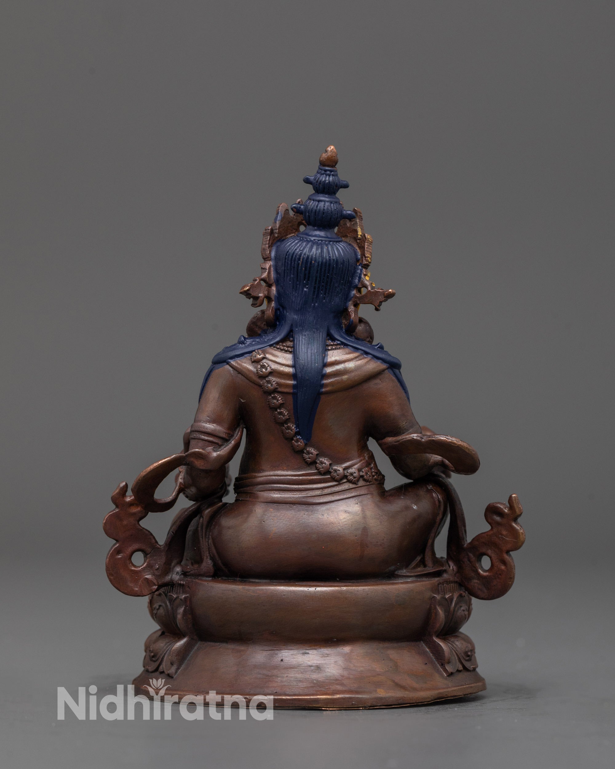 back view of Dzambhala statue highlighting sacred carvings and aged oxidized texture