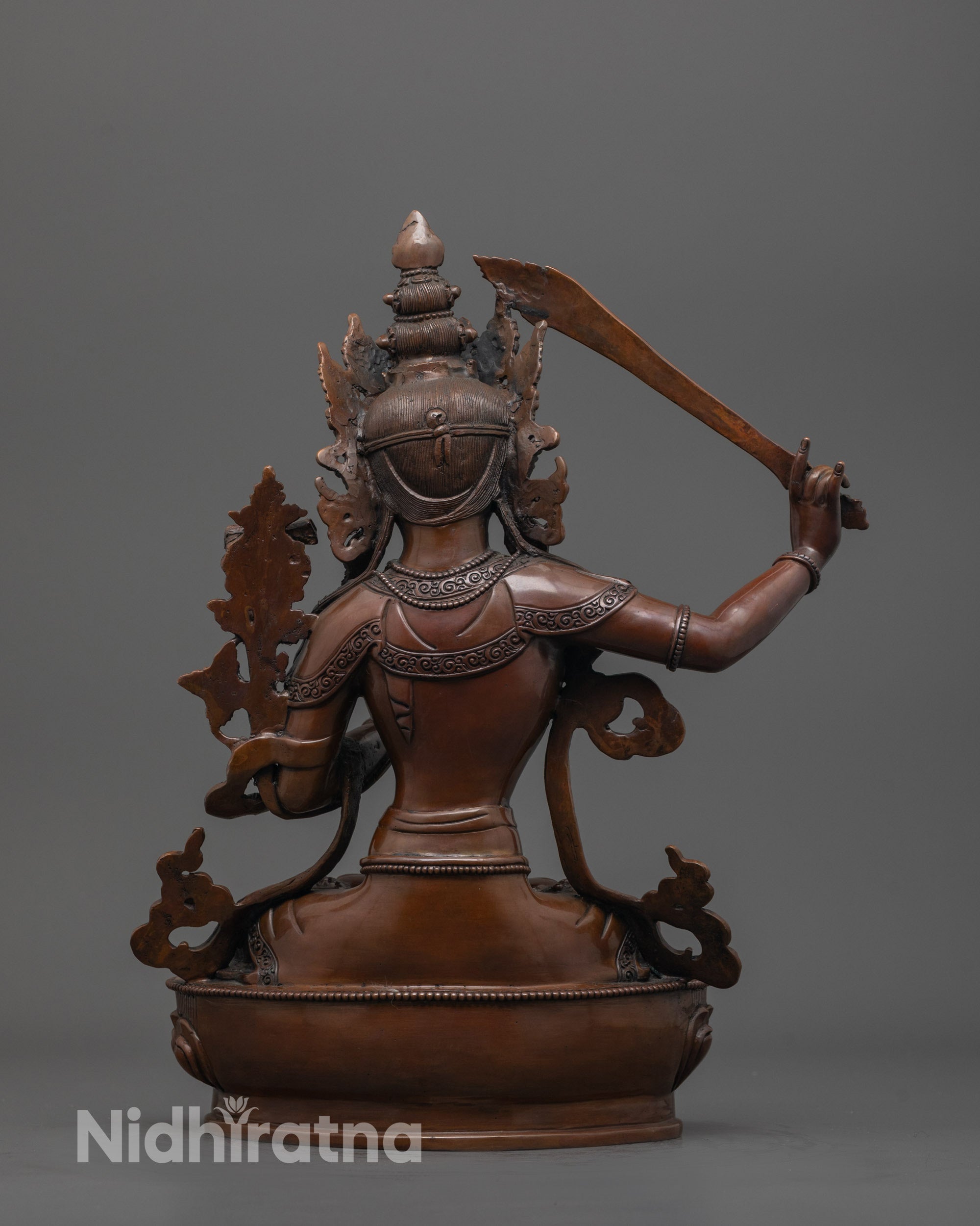 back view of Himalayan crafted Manjushri statue with smooth shiny oxidized copper finish