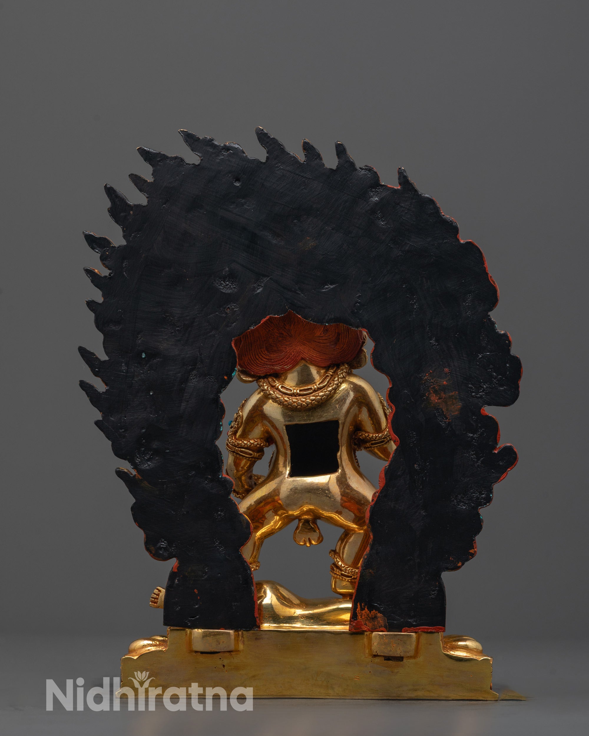 back view of black dzambhala statue revealing robe details and fire-gilded copper craftsmanship