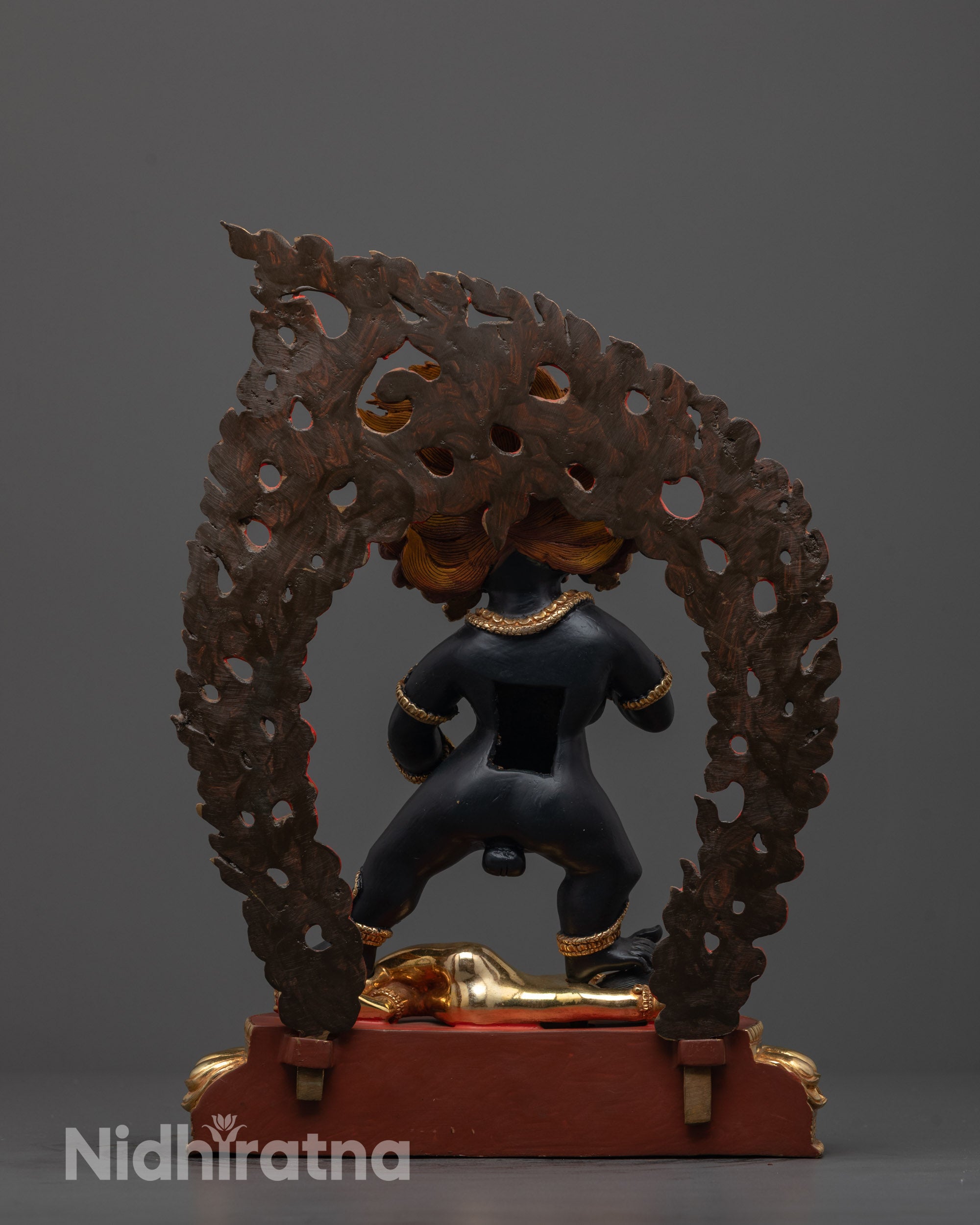 back view of black dzambhala statue showing fiery halo and ornate robe details