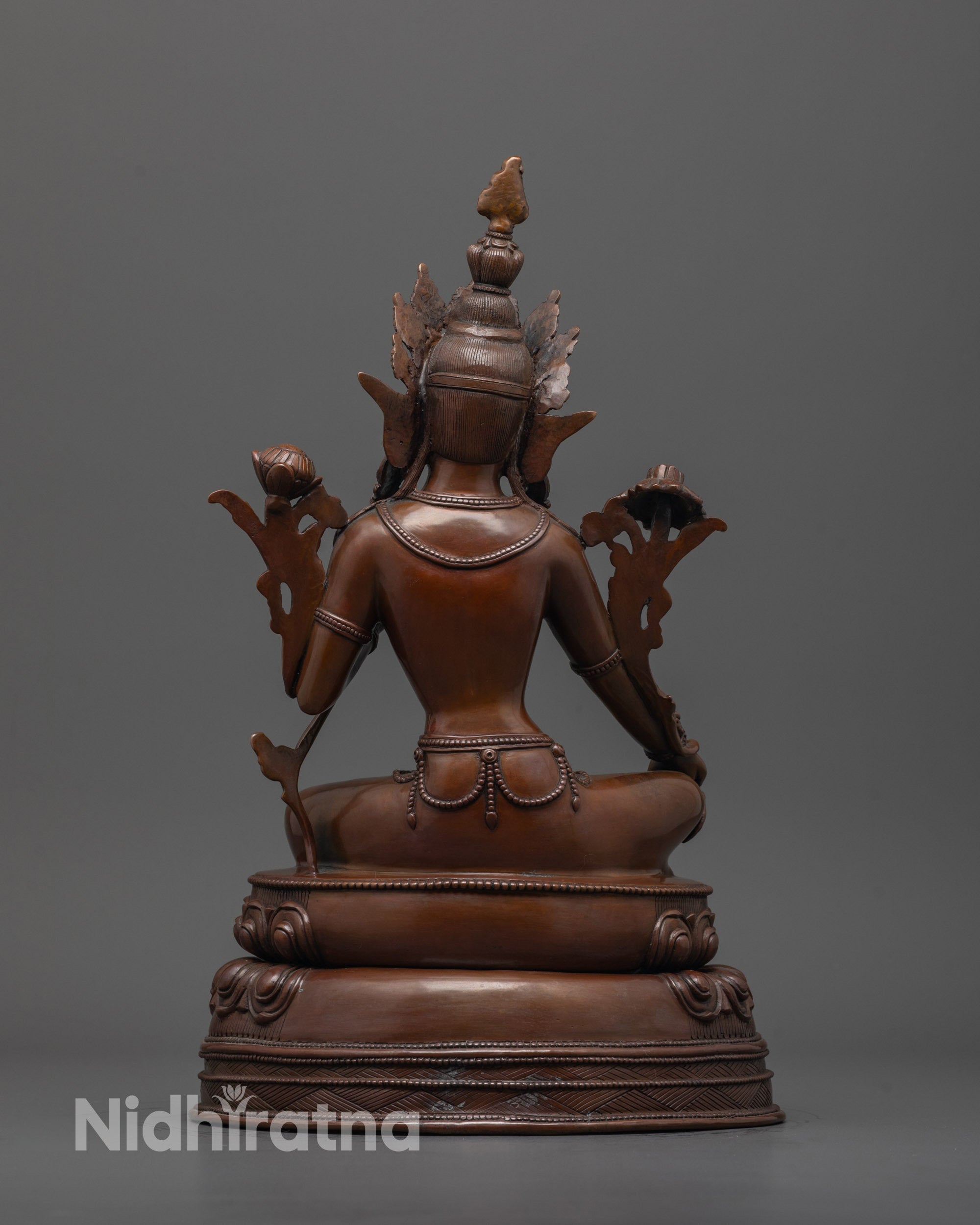 back view of dark oxidized green tara statue highlighting intricate lotus base detailing