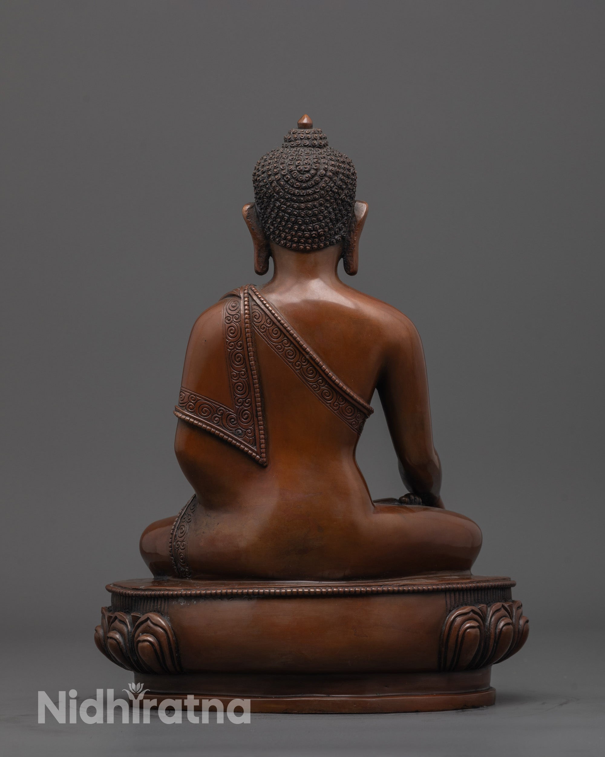 back view of oxidized Buddha statue highlighting intricate patterns on carved robe