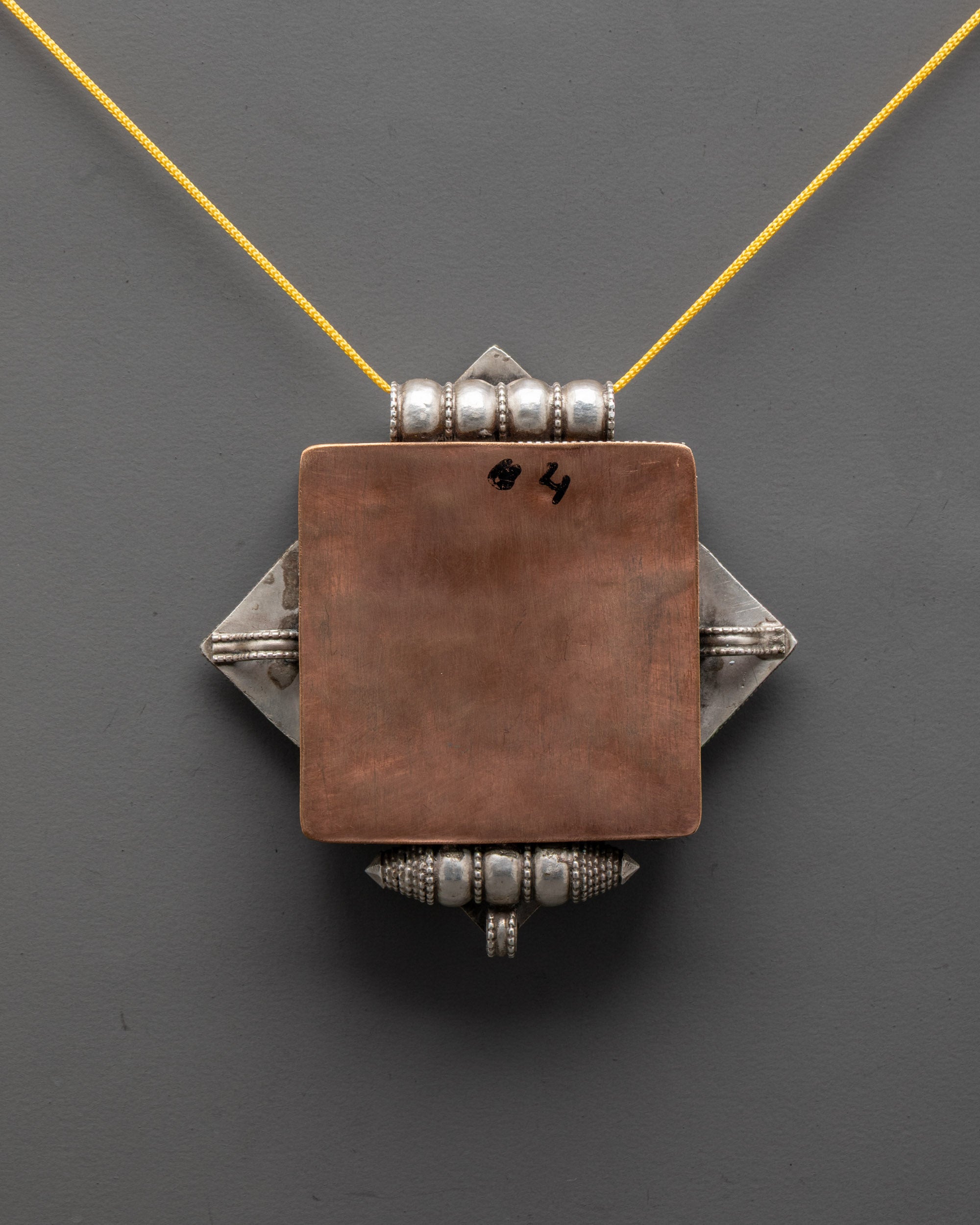 back view of silver dharma wheel locket showcasing finely detailed artisan filigree design