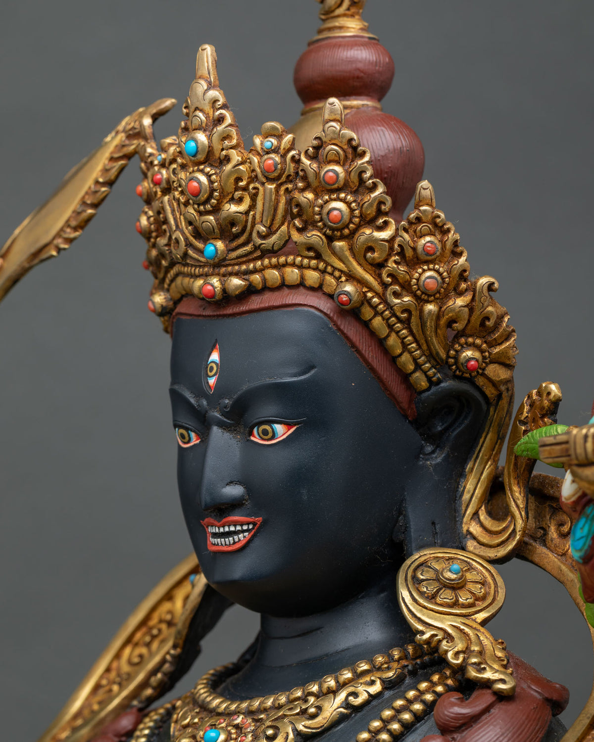 Black Manjushri statue profile close-up with gold crown inlaid with turquoise and coral gemstones