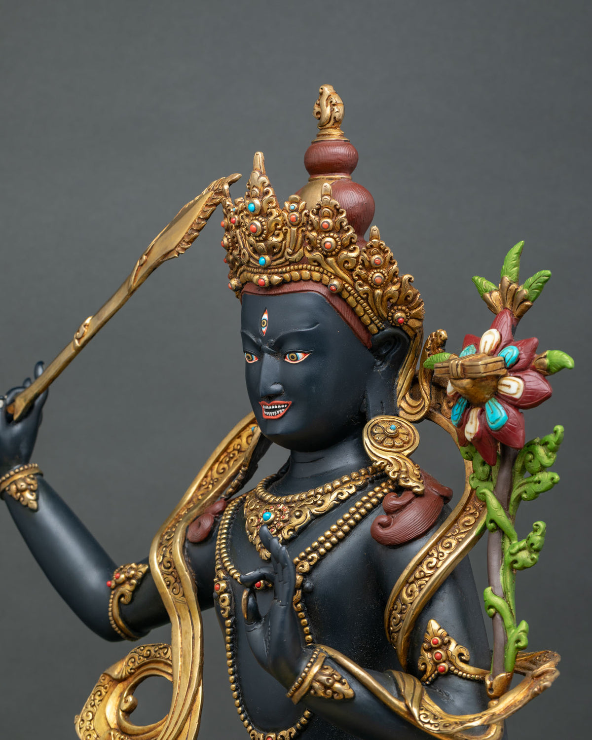 Black Manjushri statue wielding flaming sword of wisdom and holding lotus with Prajnaparamita Sutra