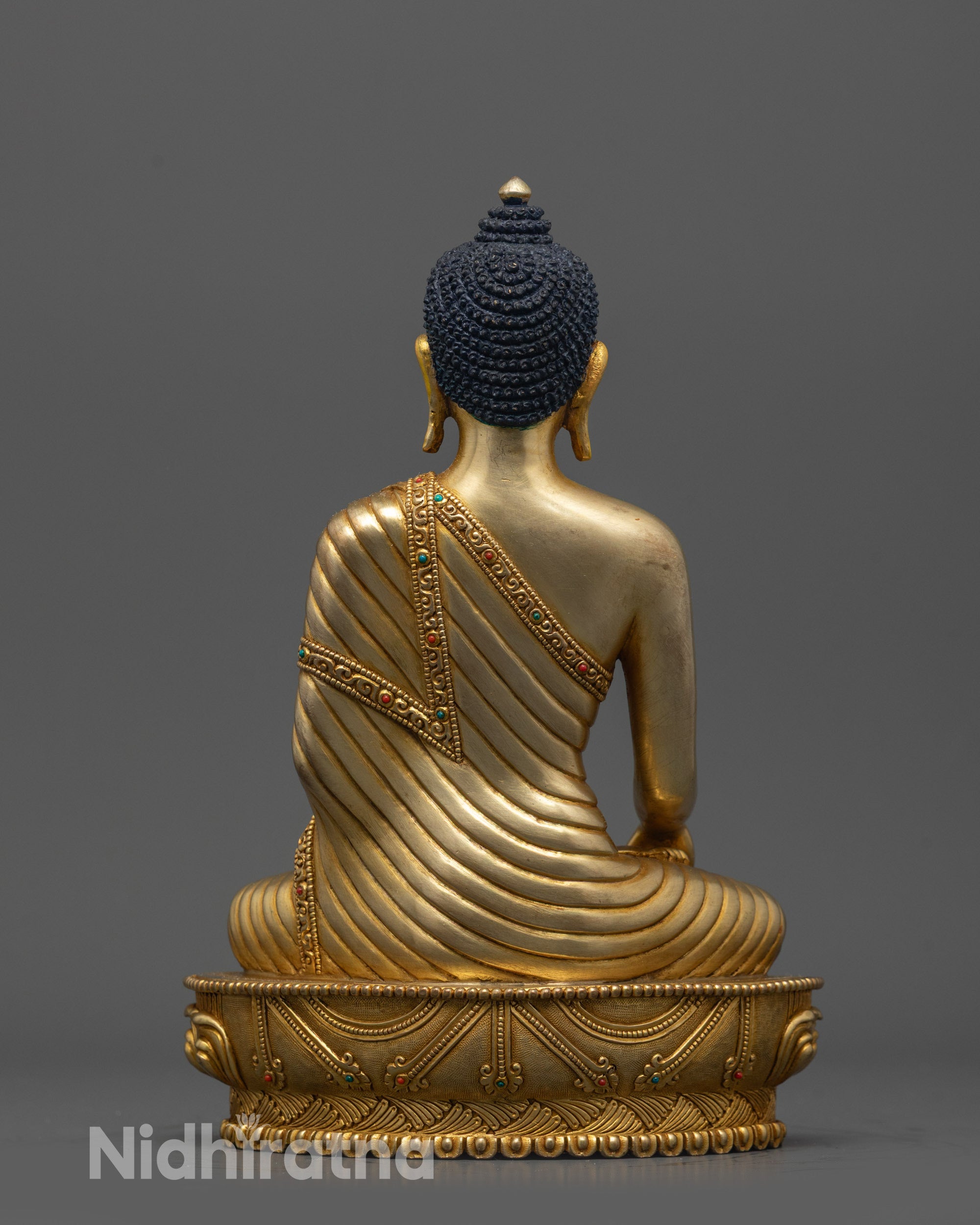 Back view of Buddha statue showing carved robe patterns and gold fire-gilded body