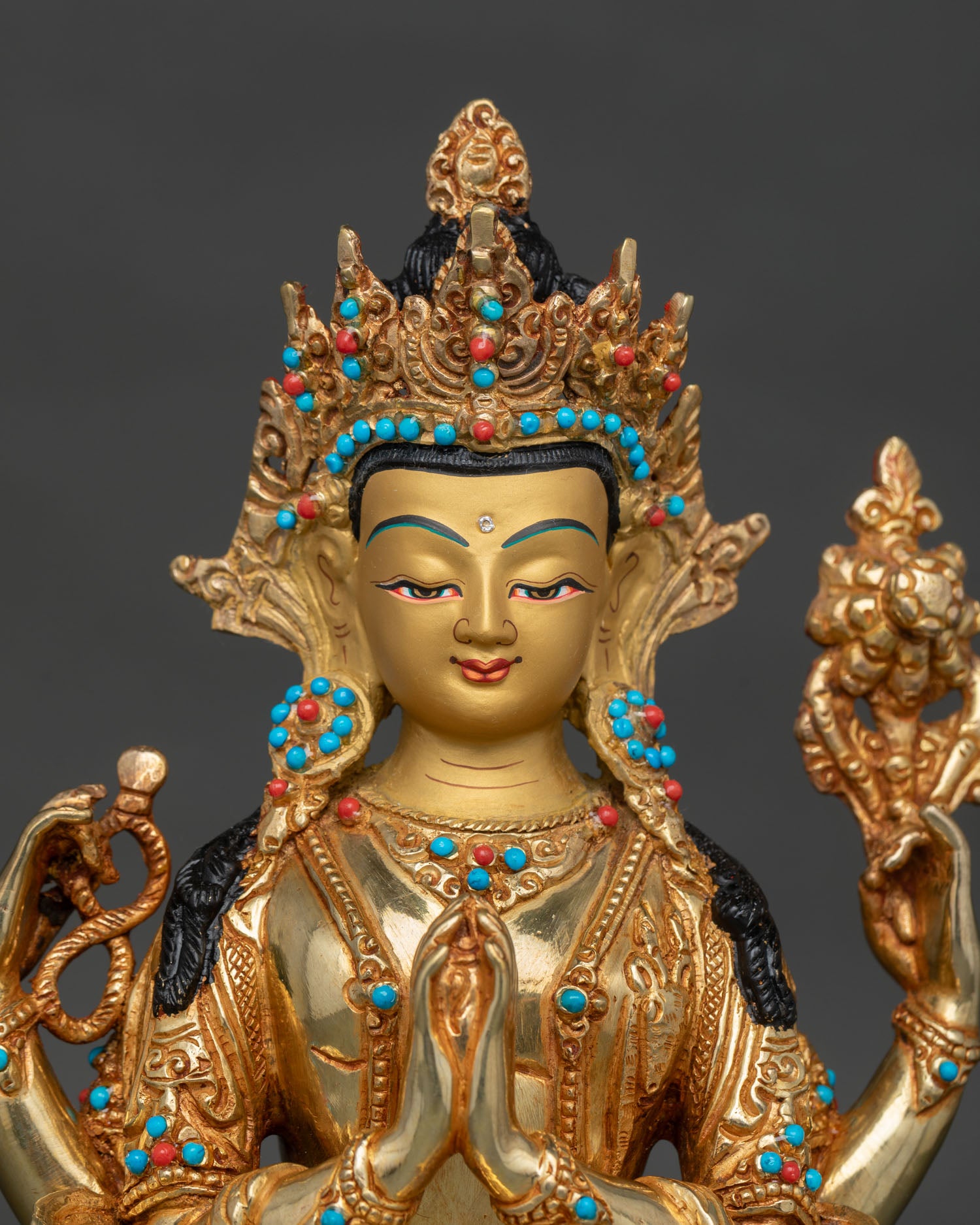 Chenrezig face with gold-painted details, turquoise, and coral stones.