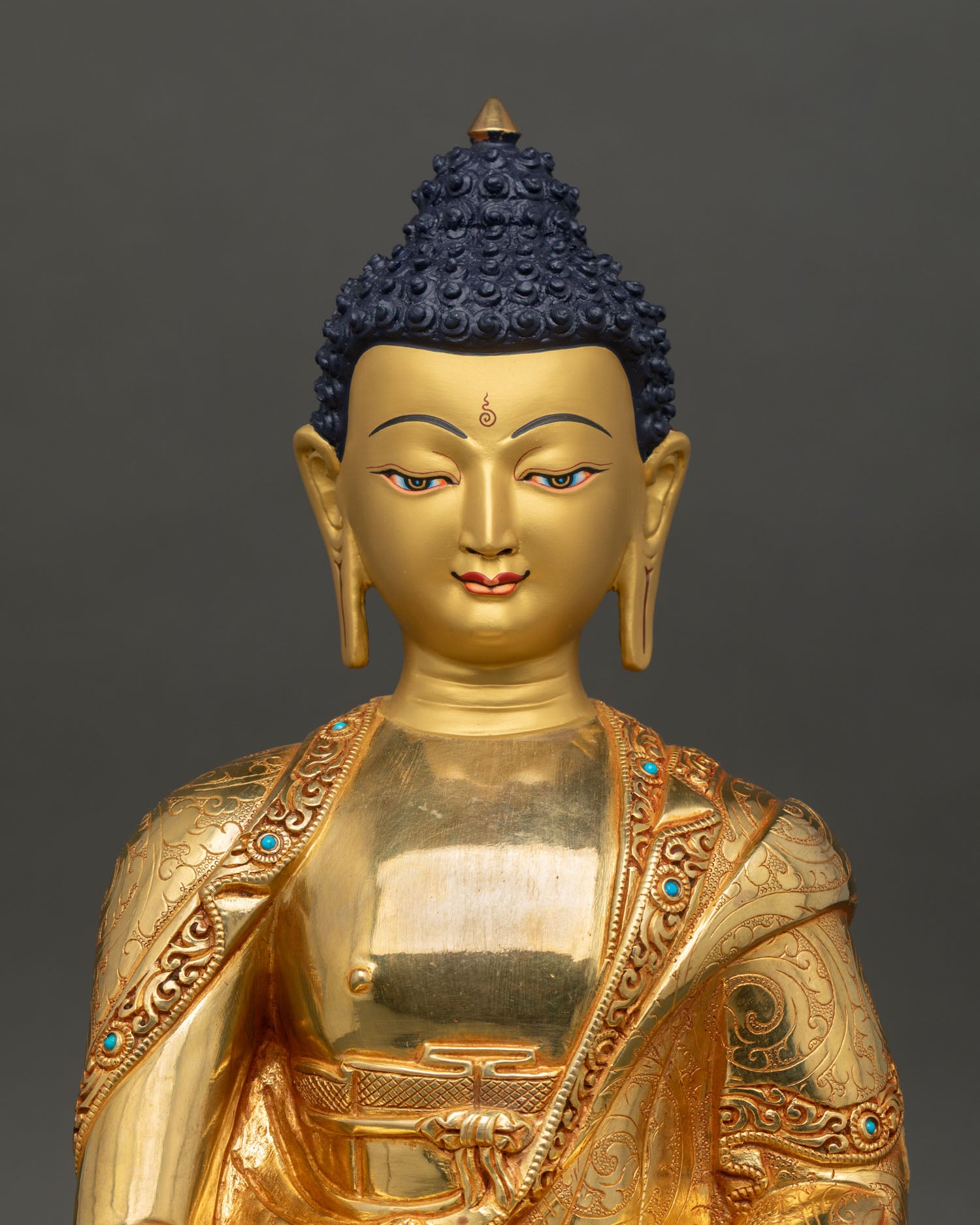 Close up view of Amitabha Buddha face showing gold painted serene expression with turquoise embellished monastic robe details