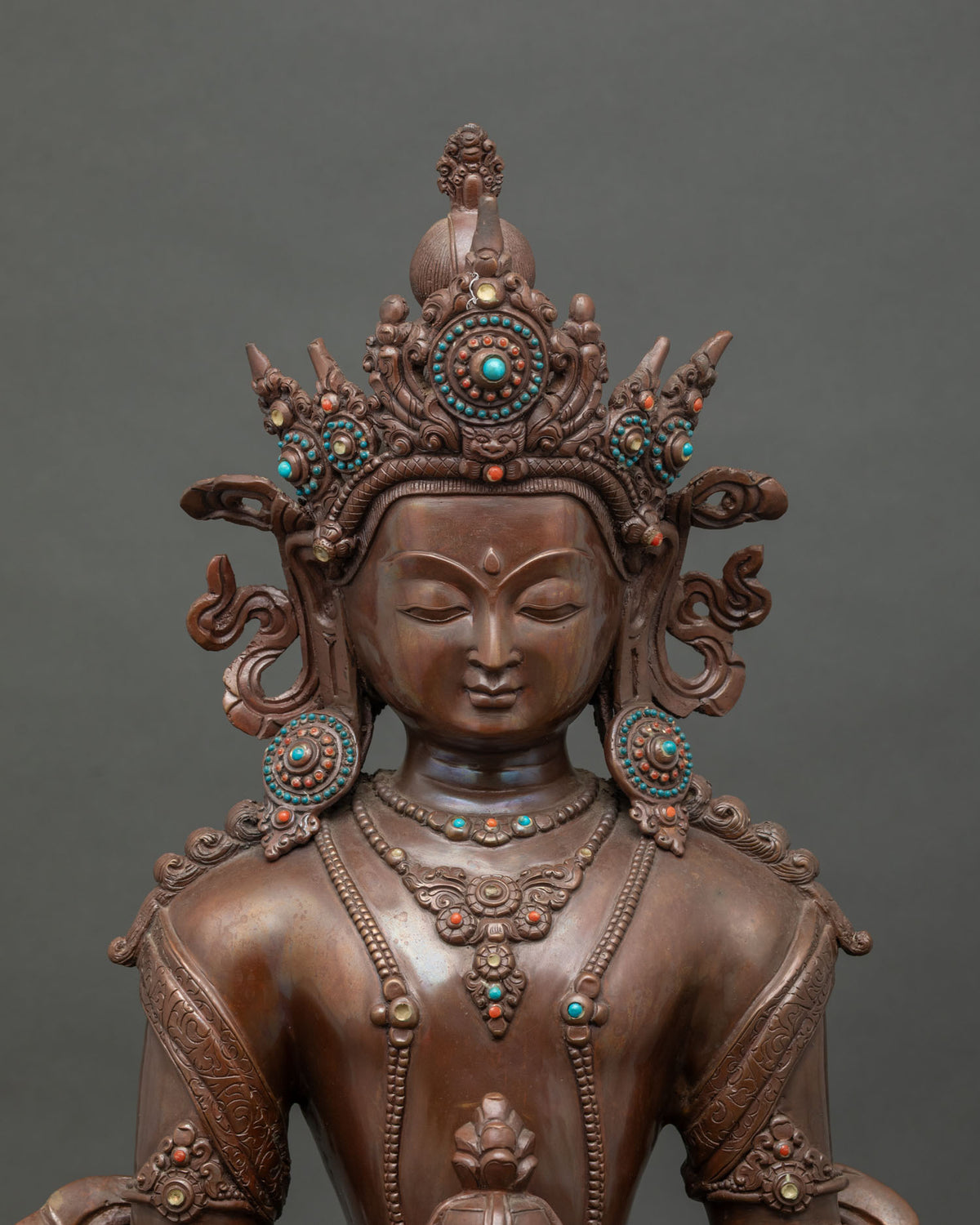 Close up Amitayus statue showing ornate jewel crown semi precious stones and celestial jewelry.