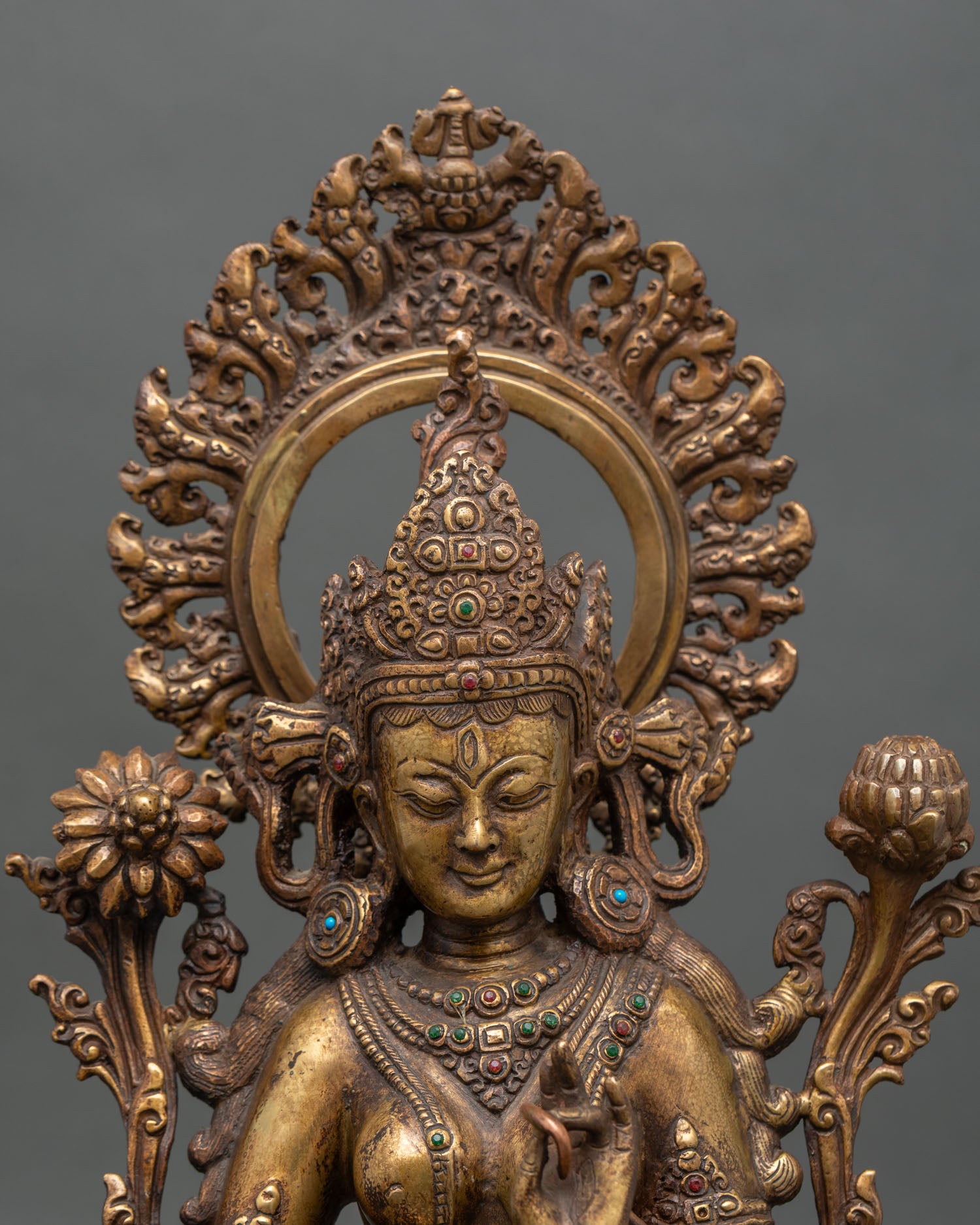 Close up of antique White Tara statue showing aged gold gilding and lotus seat details
