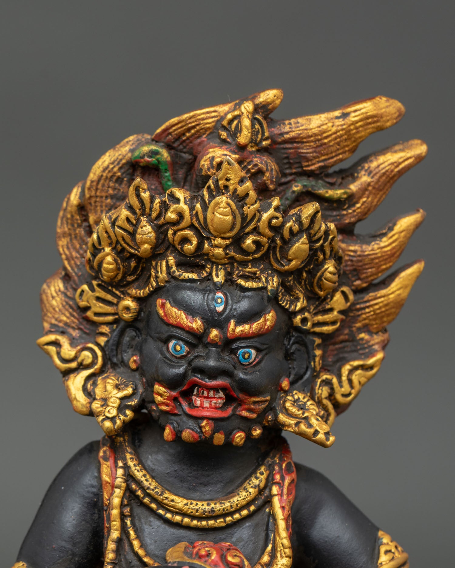 Close up Black Dzambhala sculpture detail fierce wealth deity face acrylic painted copper lost wax Nepalese craftsmanship