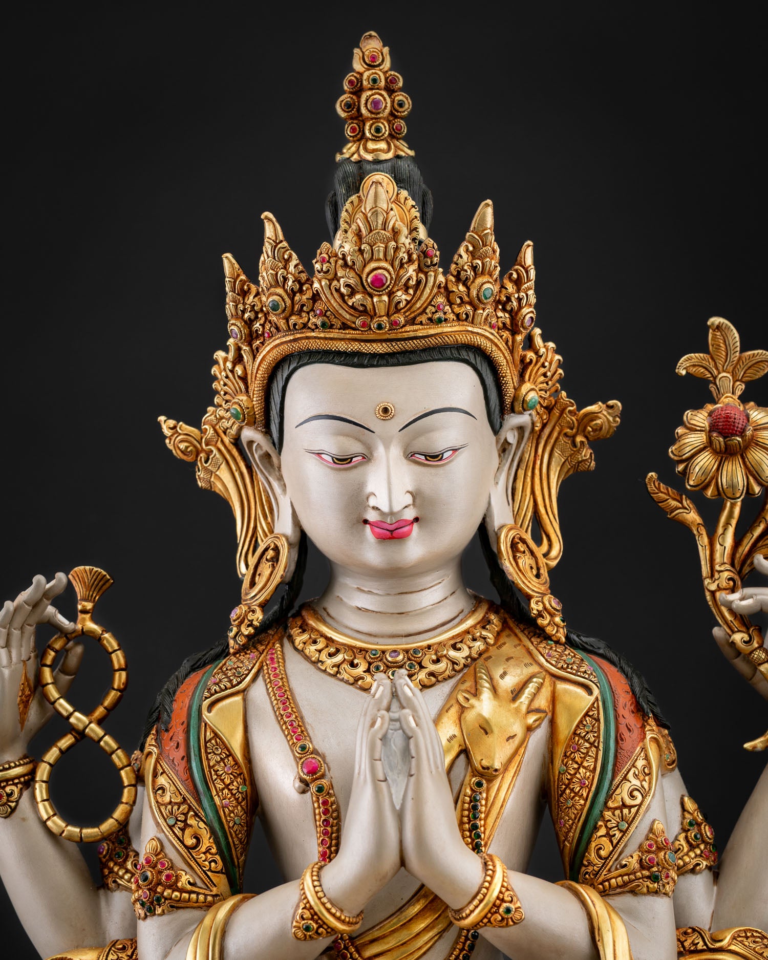 Close up Chenrezig serene face with gold gilded crown flowing robes and intricate hand painted Buddhist craftsmanship details