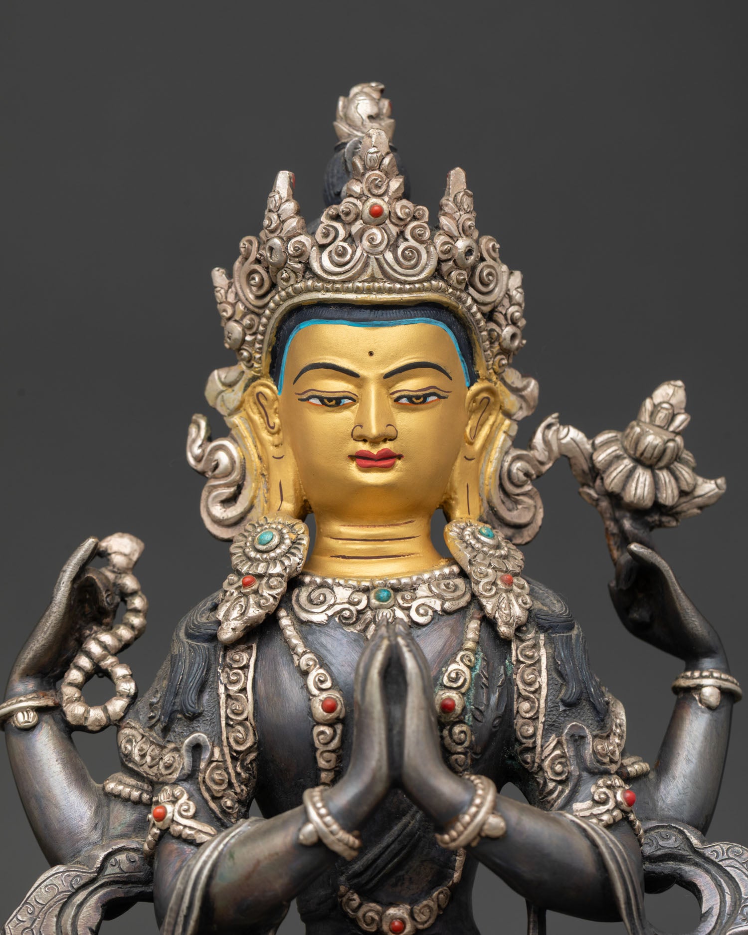 Close up Chenrezig statue gold painted face adorned with semi precious stones Nepalese Newari artisan craftsmanship sacred Buddhist deity