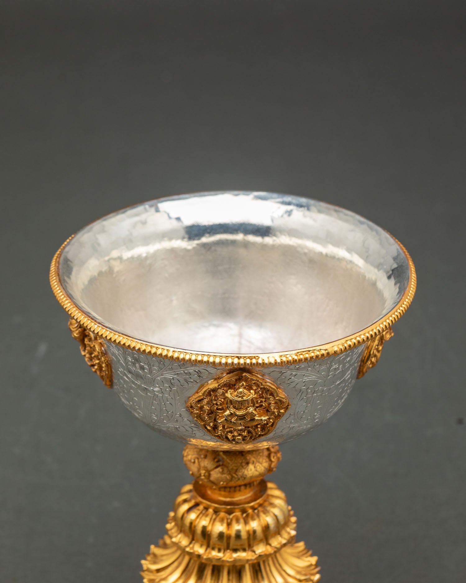 Close up detail butter lamp showing intricate sacred carvings copper craftsmanship and refined gold and silver plated Himalayan artistic design