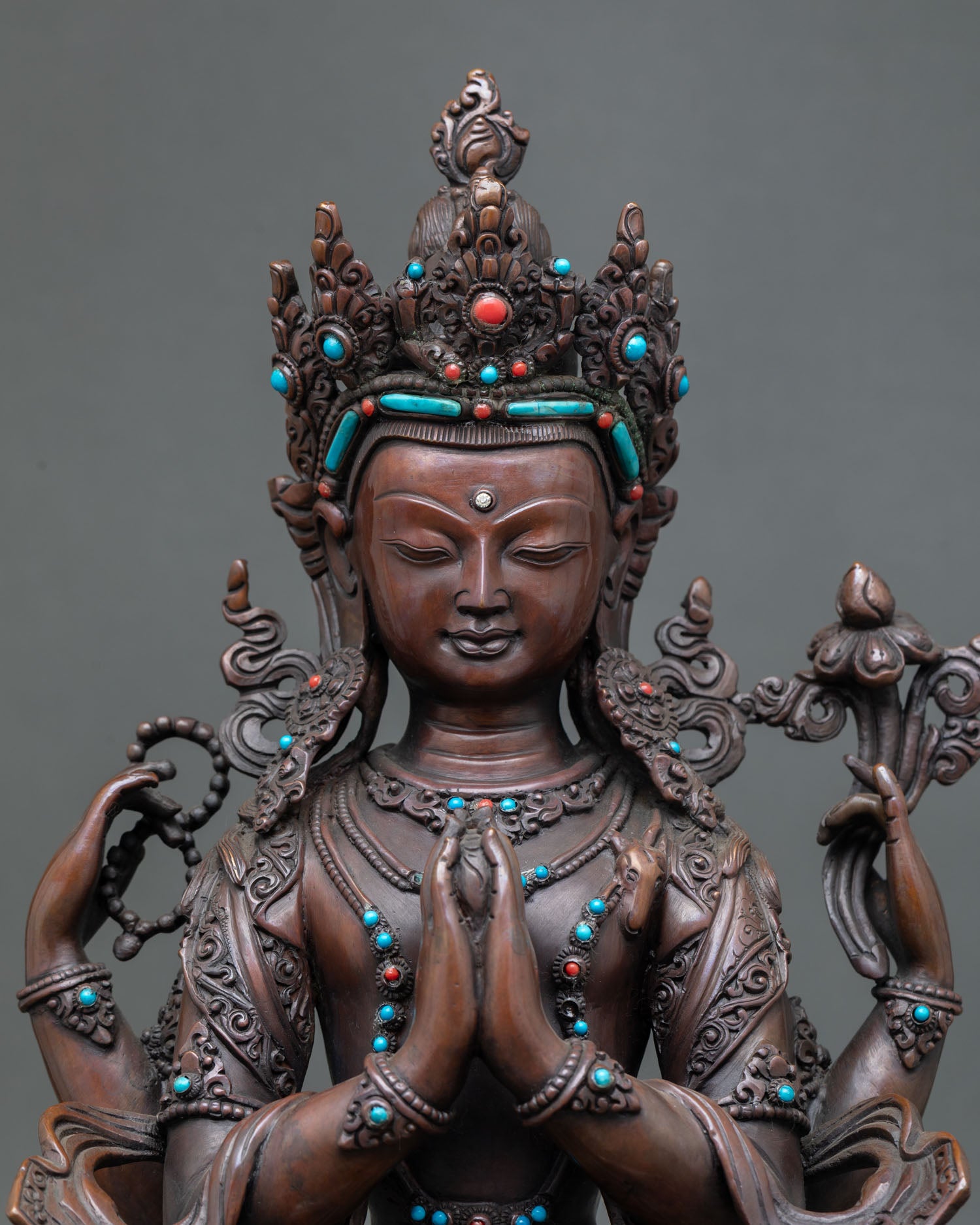 Close up detail of Chenrezig face and four armed form showing closed eyes crystal mala lotus flower and sacred hand gestures crafted by Newari artisans