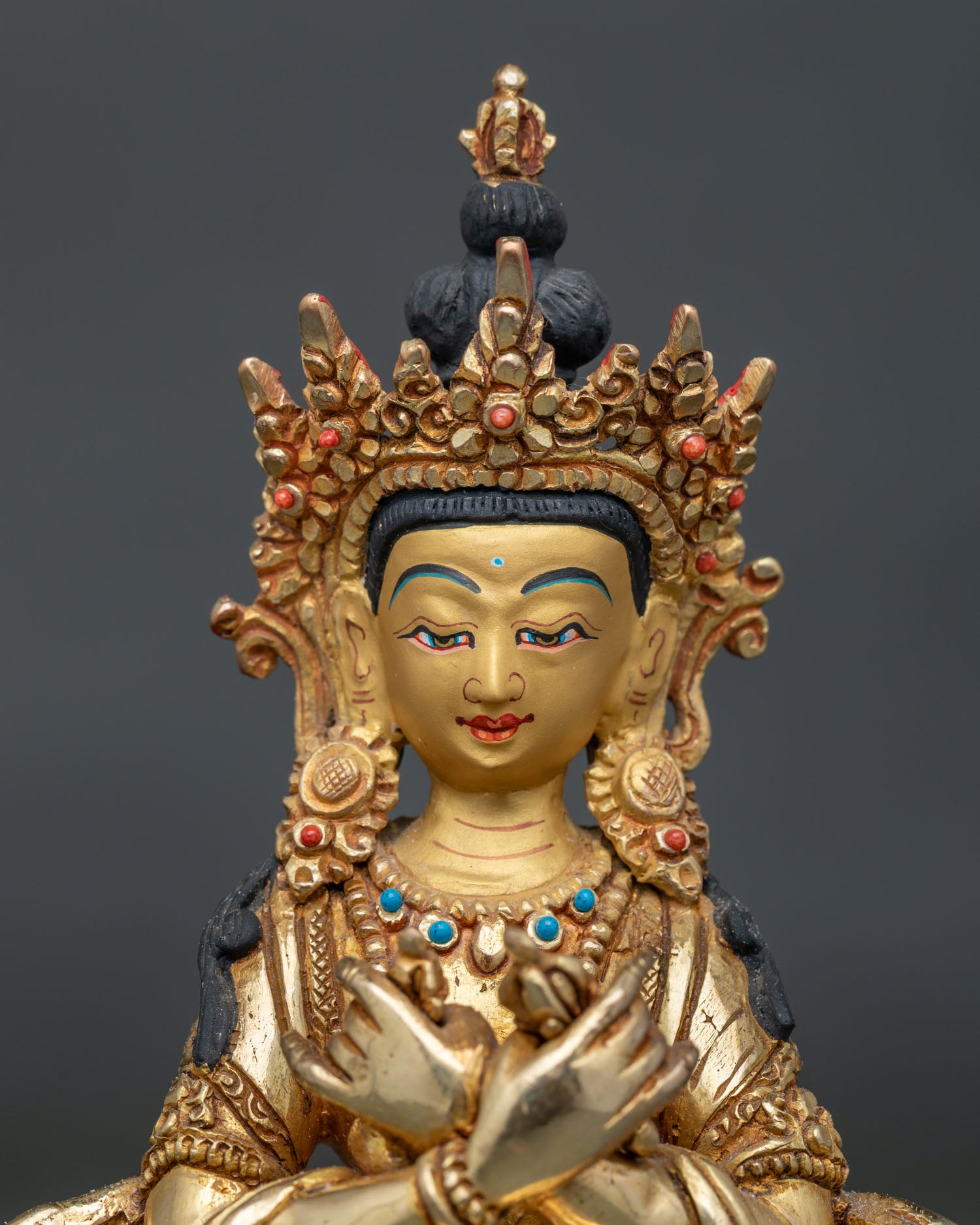 Close up detail of Vajradhara Buddha statue showing gold painted face and intricate Newari craftsmanship.