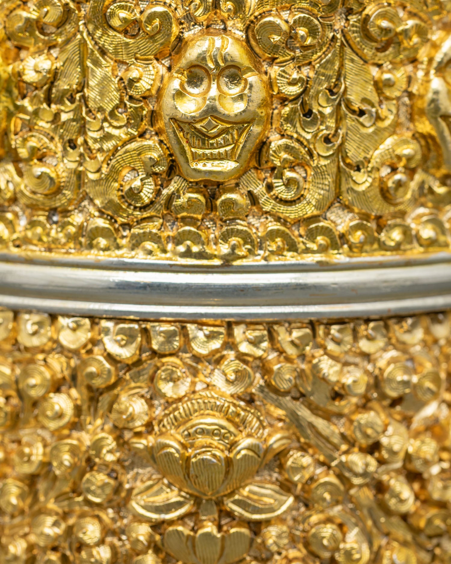 Close up detail of rice offering vessel showing intricate vajra skull and symbolic engravings with gold plated and silver plated Himalayan craftsmanshipv