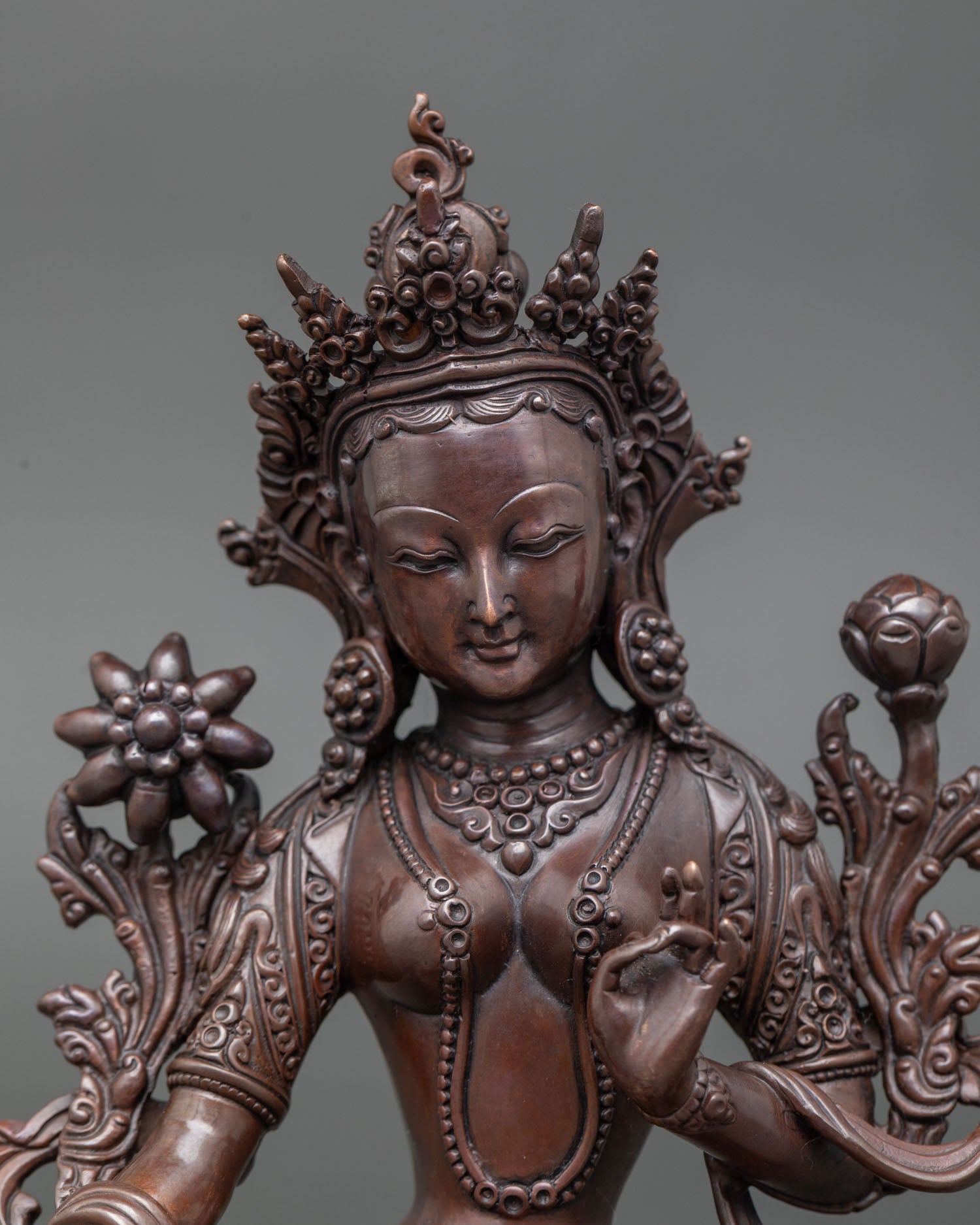Close up detailed view Green Tara Buddhist statue showing utpala lotus stem, divine feminine energy oxidized copper sculpture