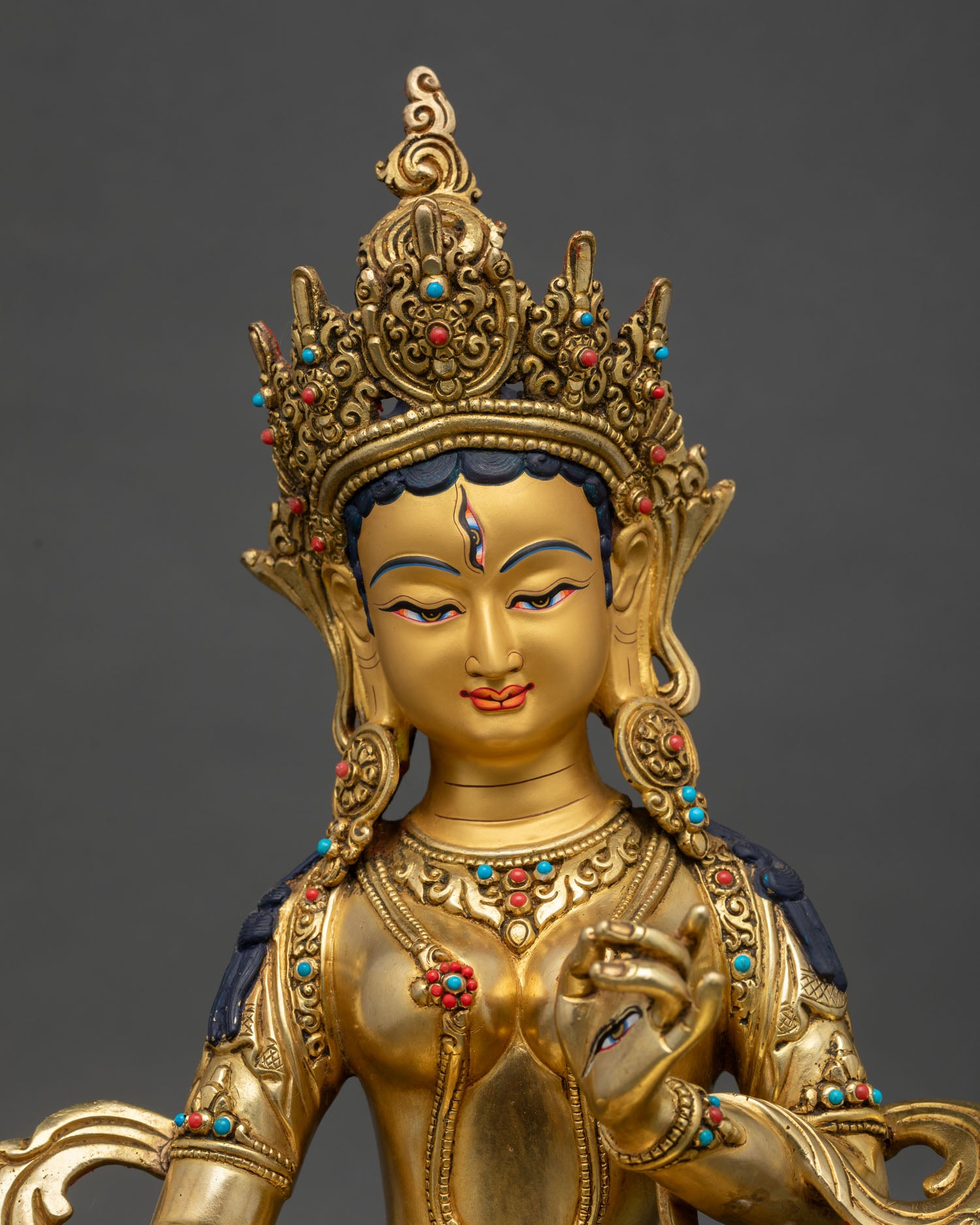 Close up Dukar statue showing intricate Nepalese craftsmanship with ornate crown semi precious stone inlays and detailed gold painted facial features